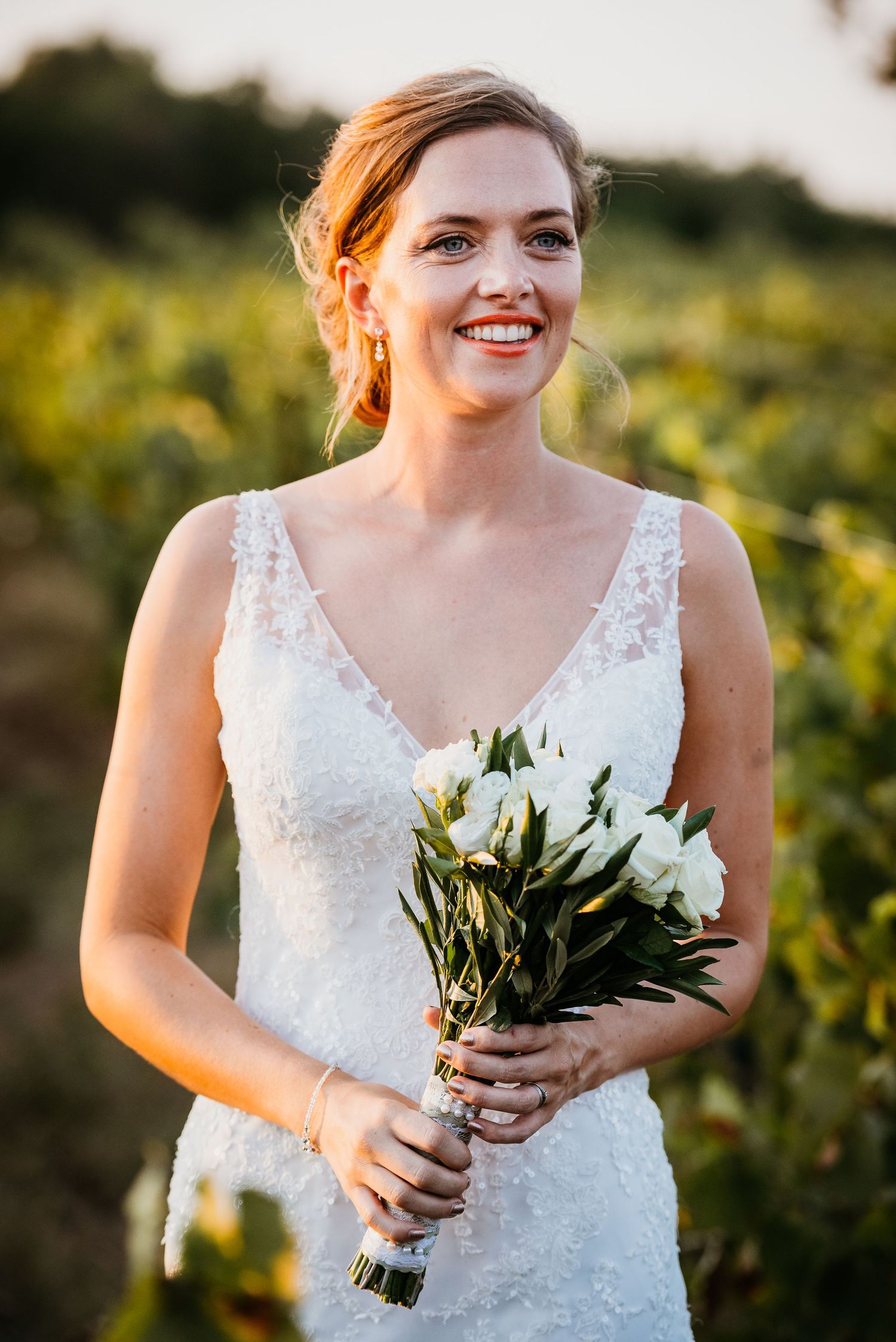 Elegant white bouquet held against detailed lace wedding dress.