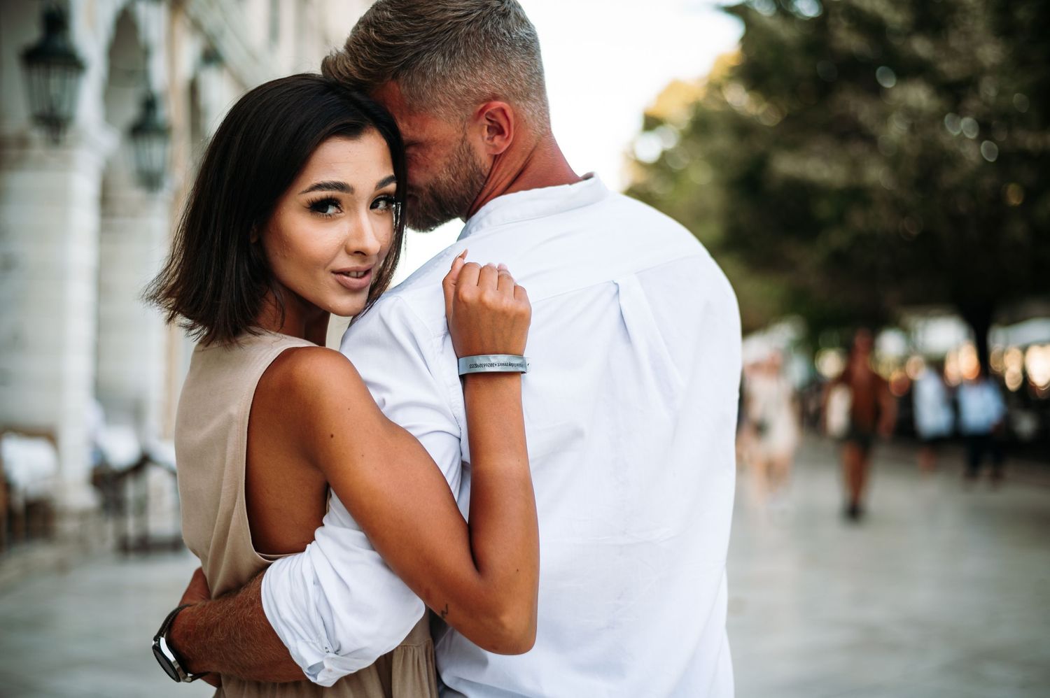 Romantic couple embracing on a European street with classic architecture in background.