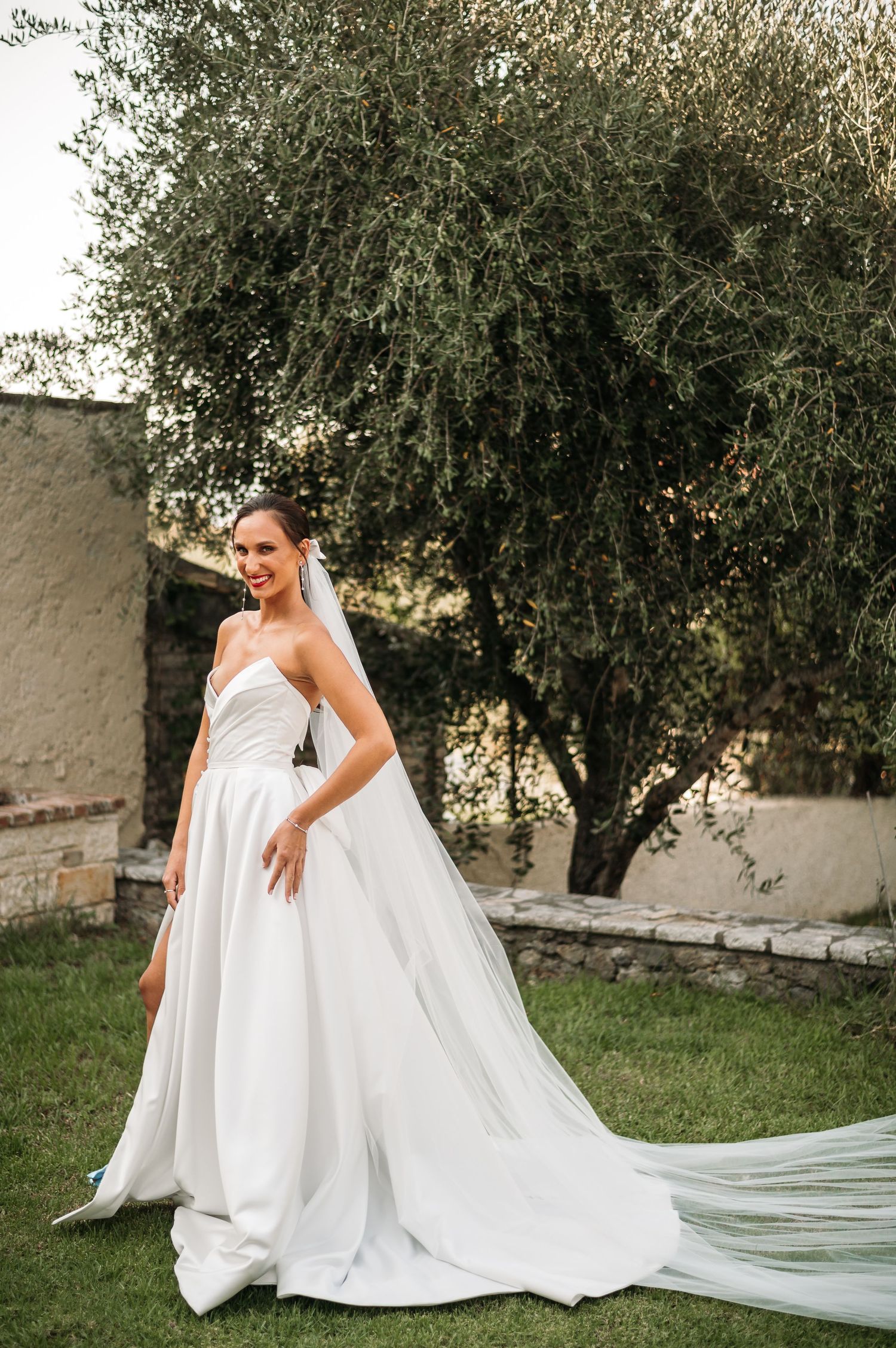Wedding dress photos in an olive garden showing the dramatic train and veil details.