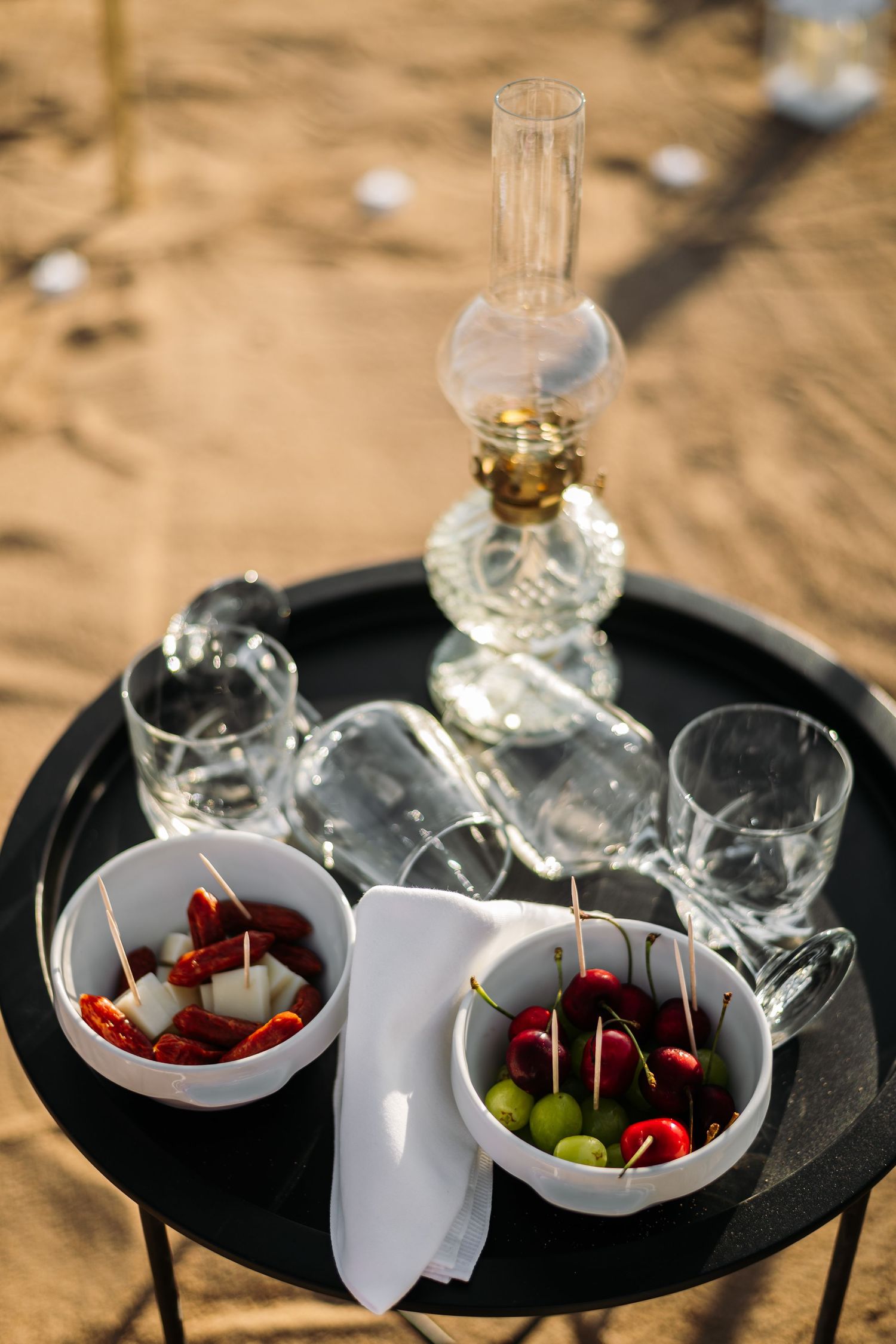 Elegant appetizer display with cherries and glasses on black serving tray.