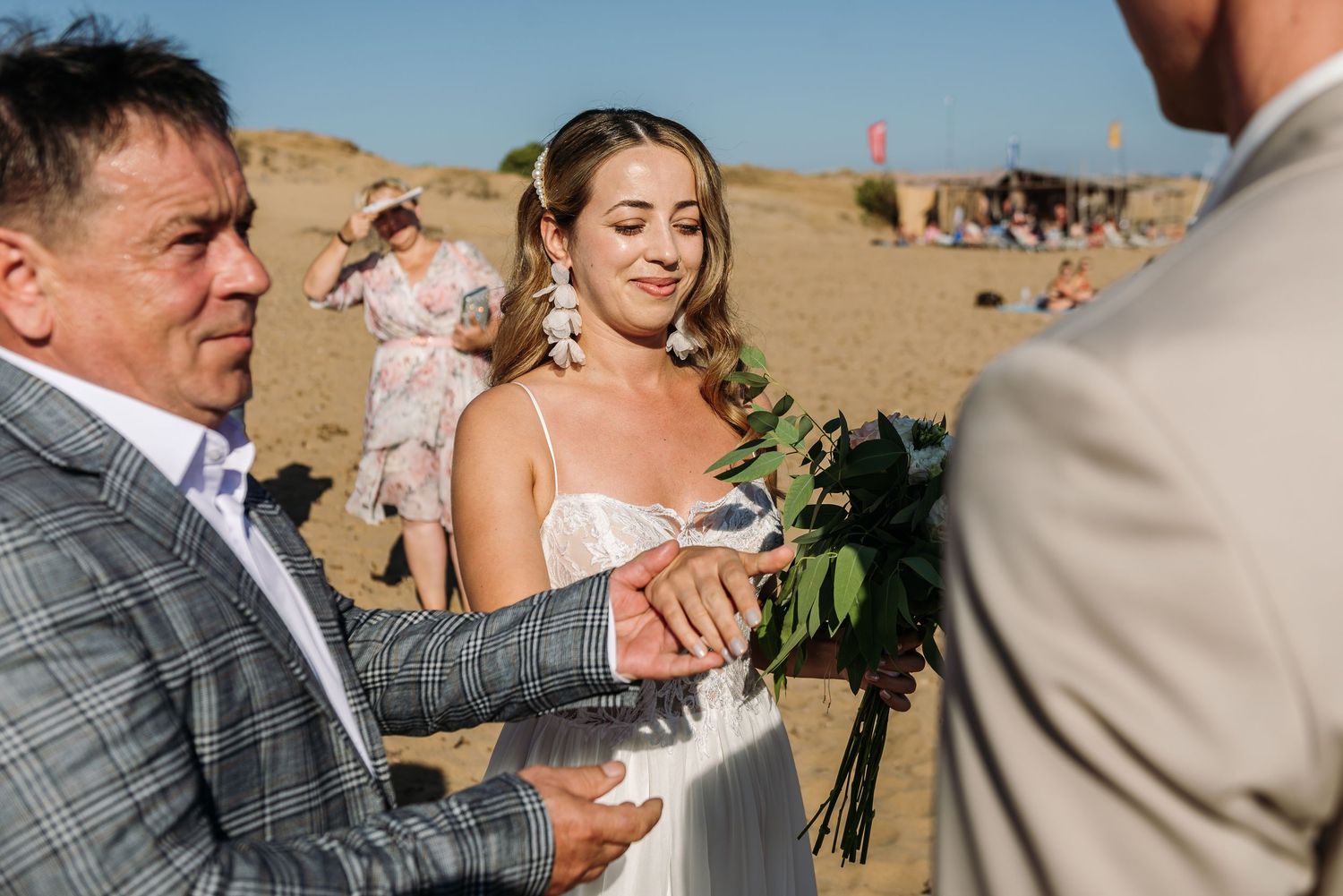 Wedding ceremony candid moments captured on sandy beach with natural lighting.