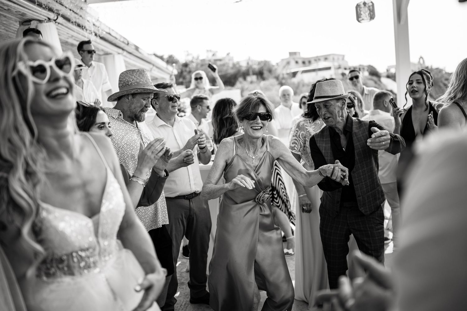 Candid moments of wedding guests celebrating and dancing at an outdoor beach venue.