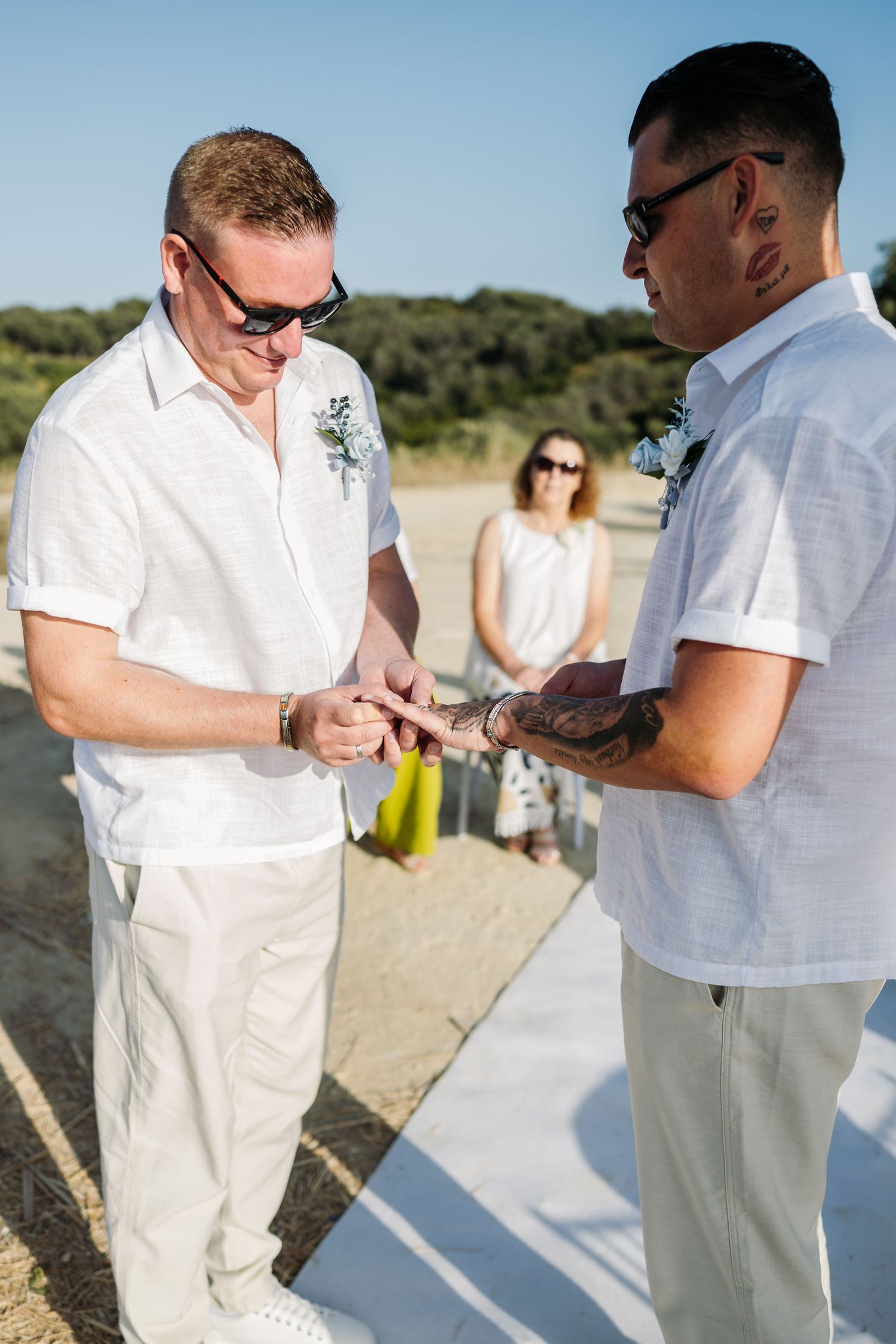 Wedding ceremony participants exchange rings during an intimate beach ceremony.