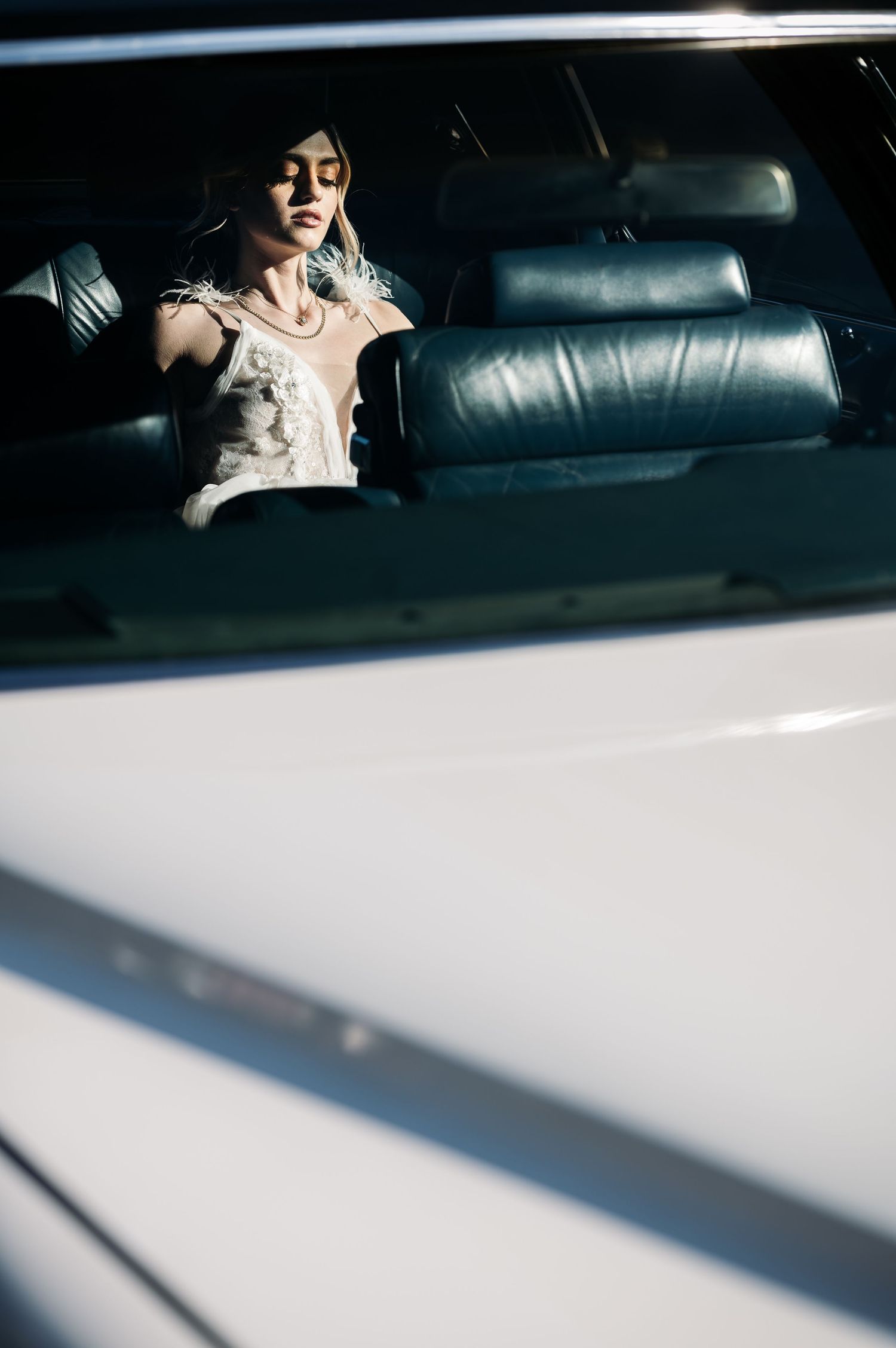 A series of car window reflections showing glimpses of a person in white clothing sitting in the backseat.