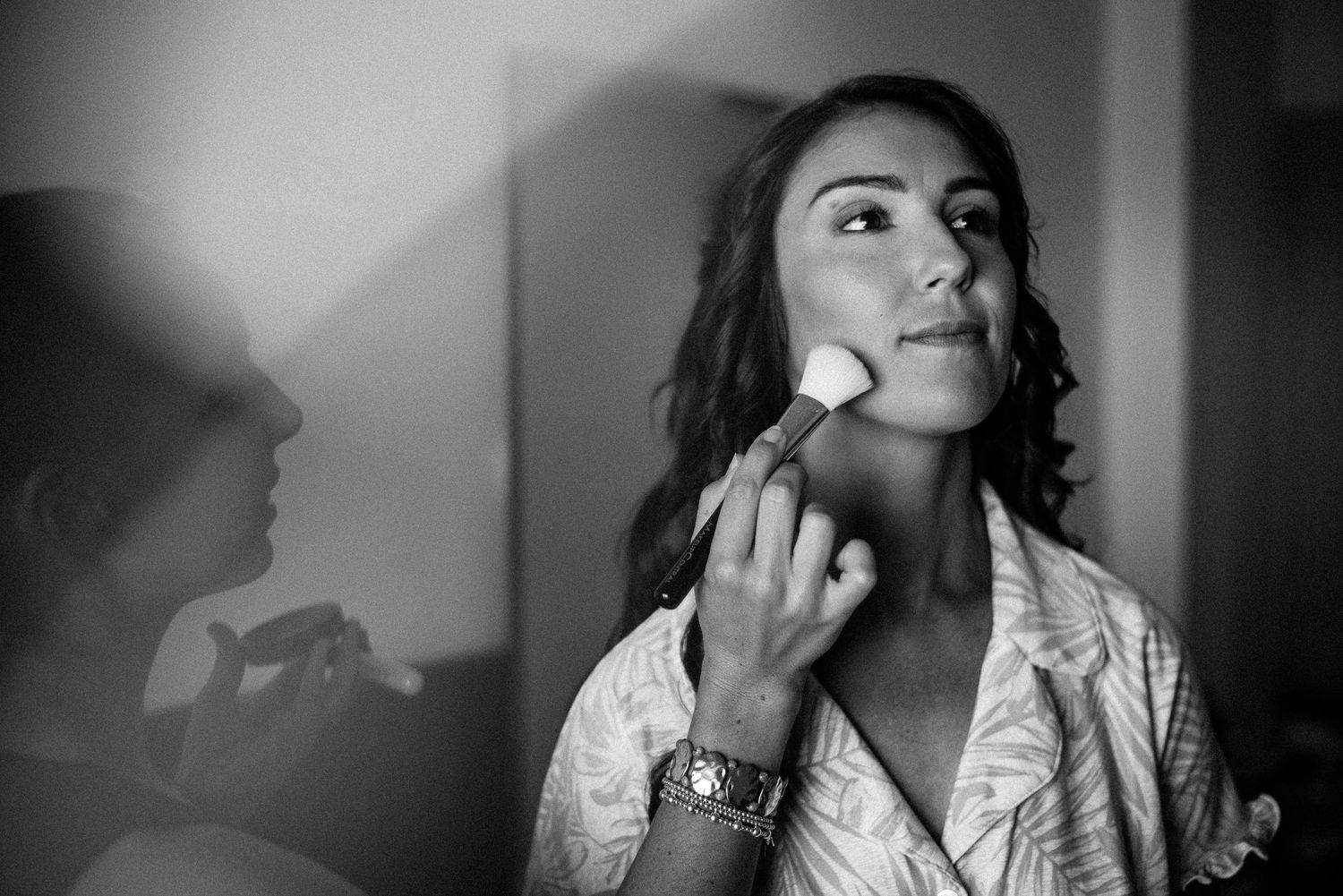 Black and white photo of someone having makeup applied before an event.