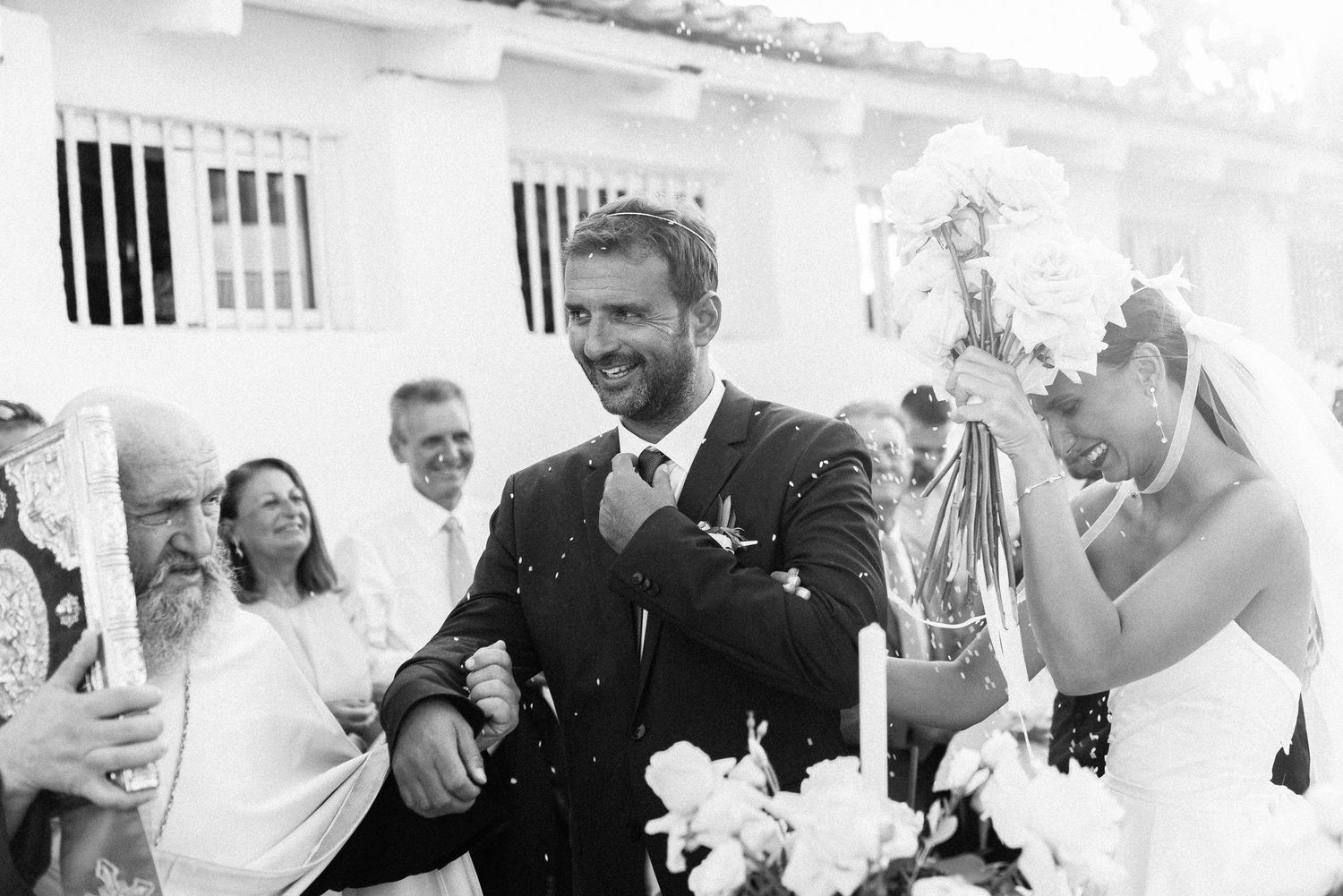 Black and white photo of wedding party celebrating with champagne outdoors.