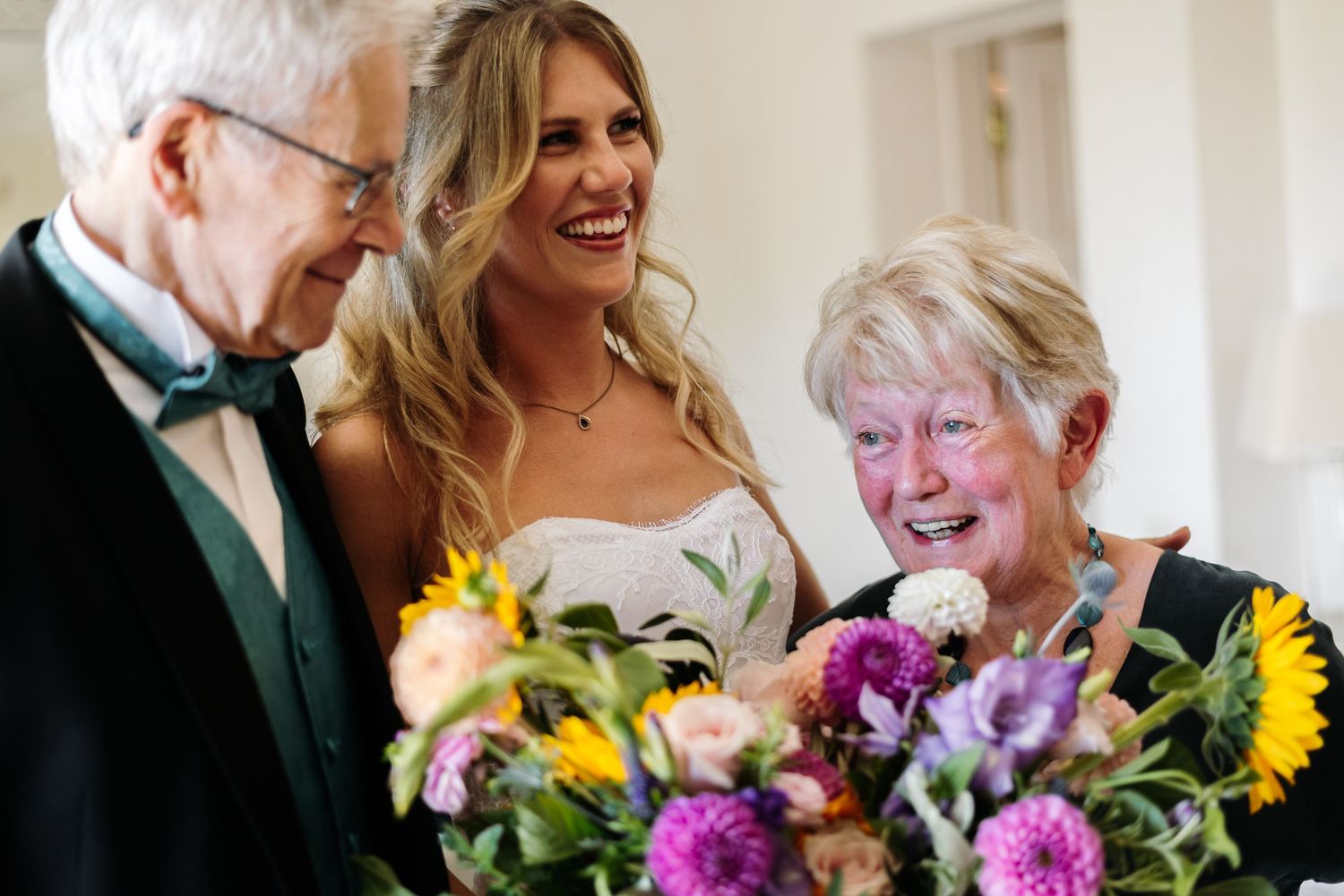 Joyful wedding moment with colorful bouquet featuring sunflowers and purple blooms.