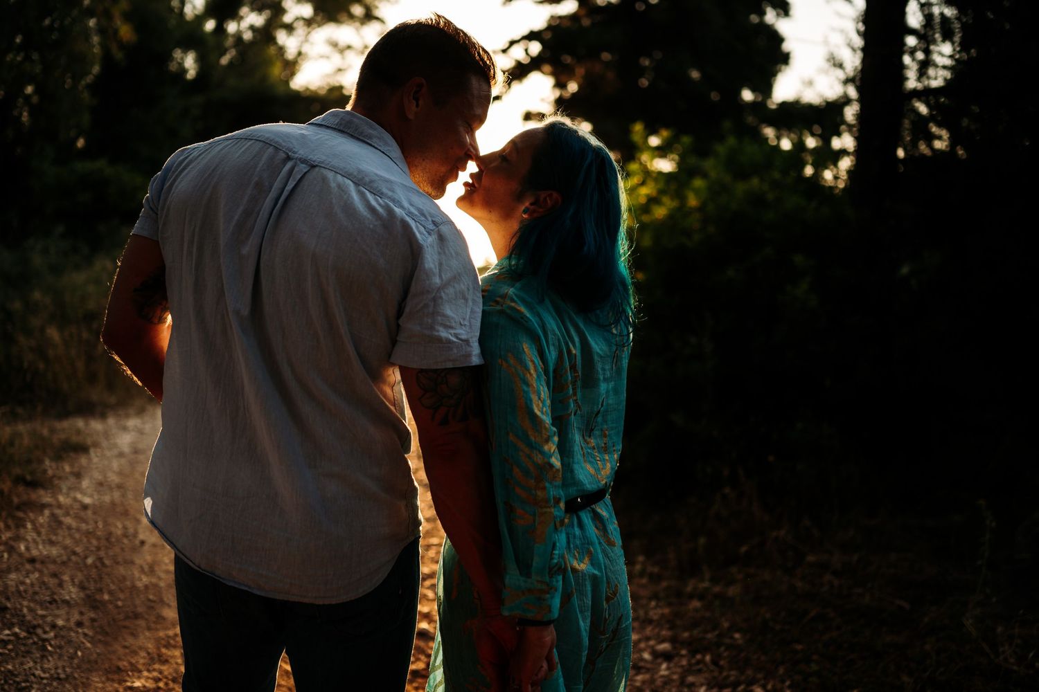 Silhouettes of a couple share an intimate moment against a golden sunset backdrop.