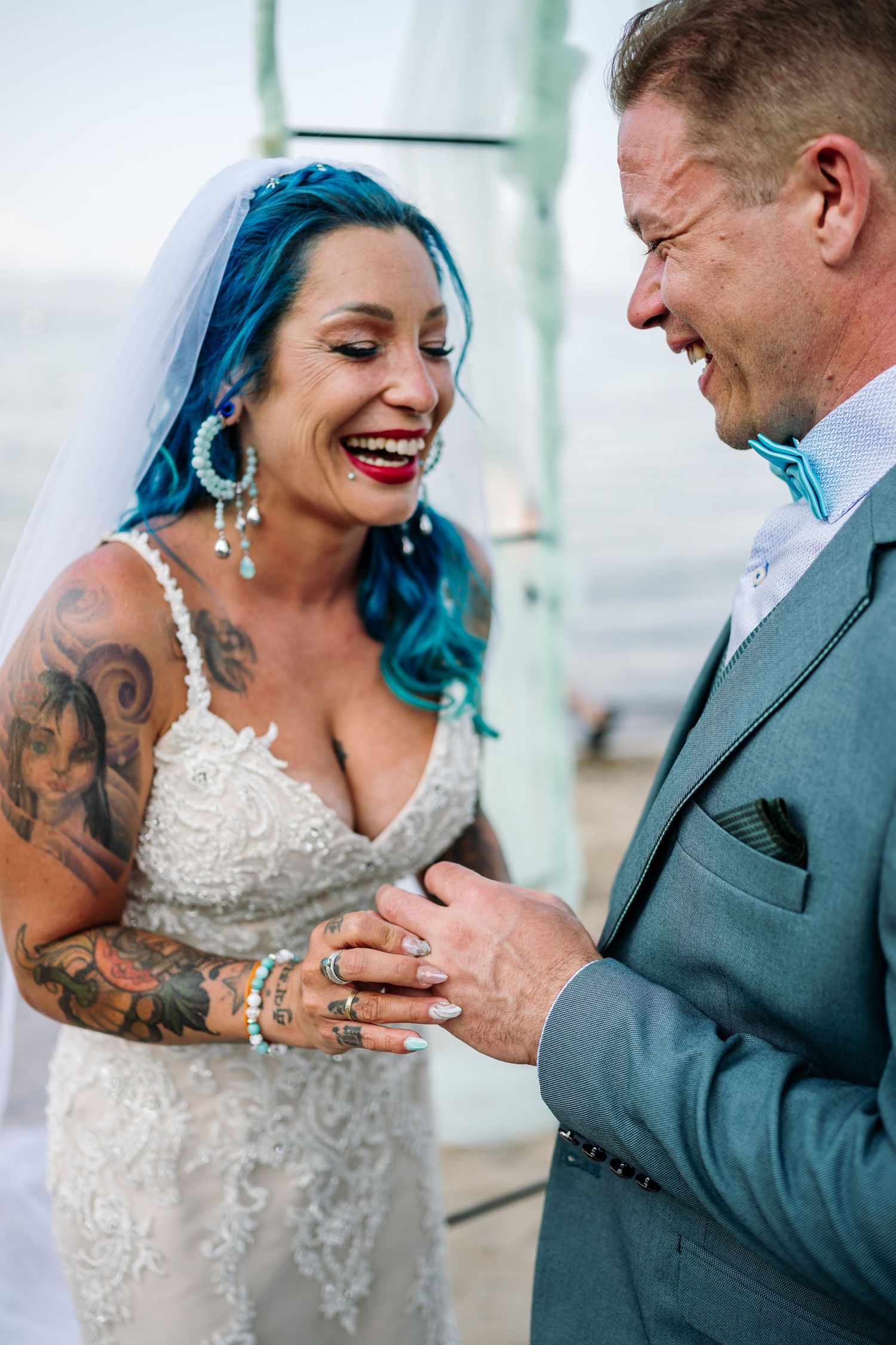 A couple laughs together during their wedding ceremony by the ocean.