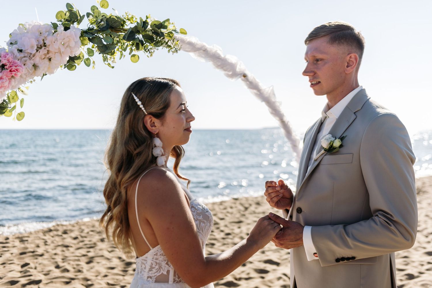 Intimate beachside wedding ceremony showing exchange of rings at sunset.