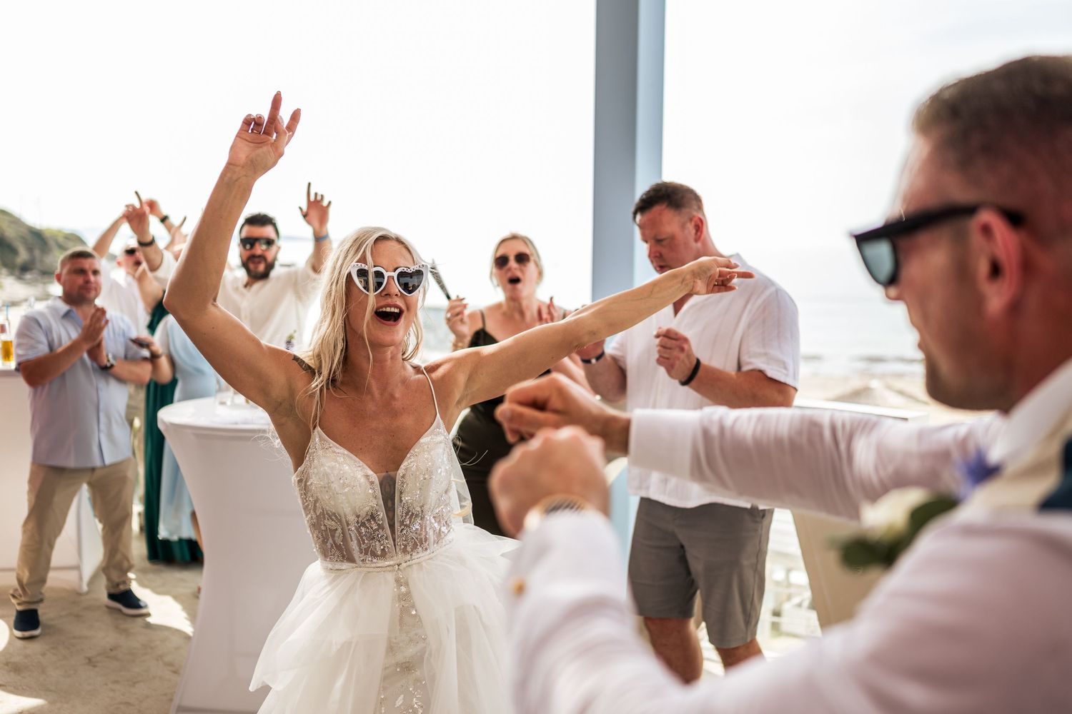 Energetic dancing and celebration during a beachside wedding reception.
