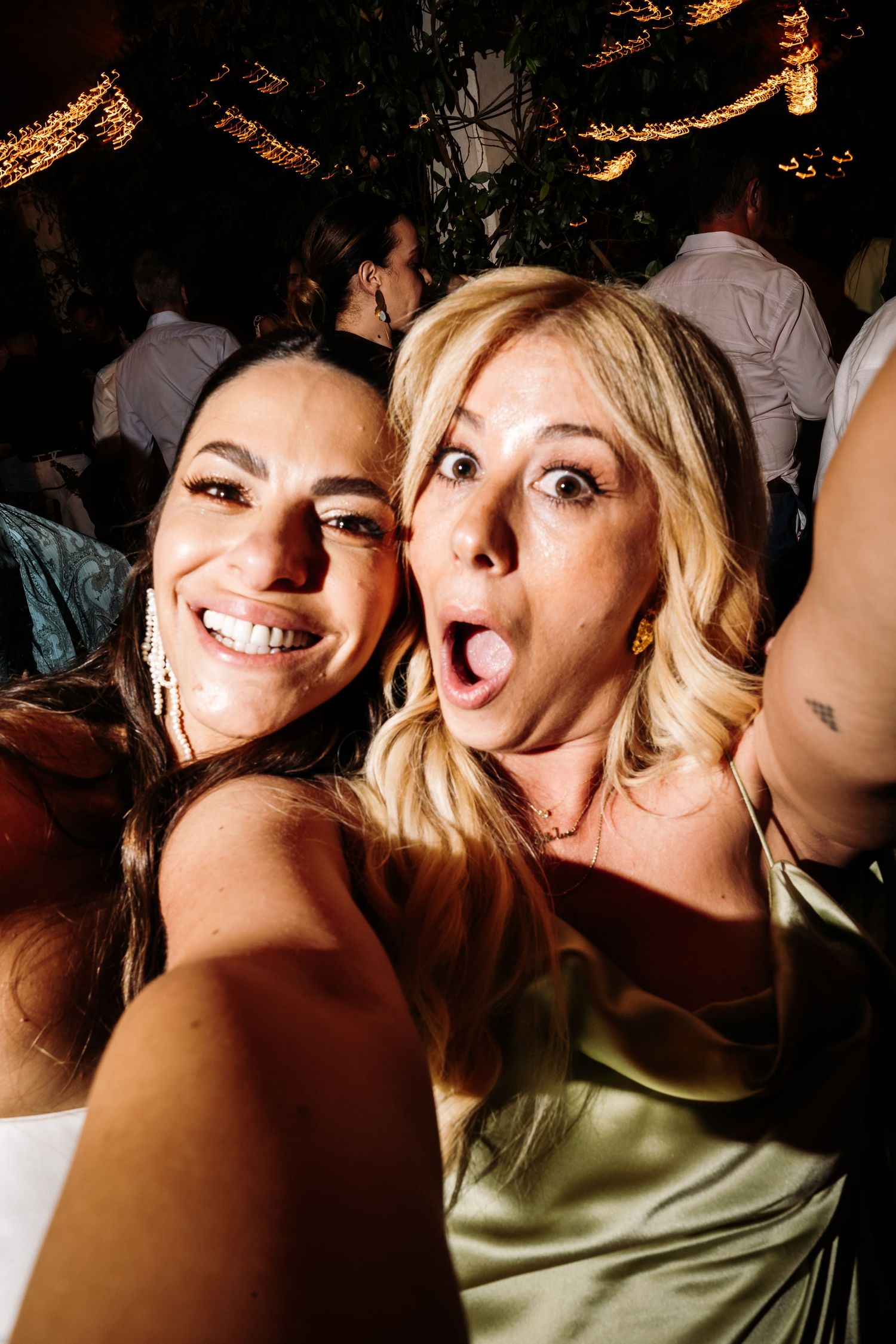 Friends pose for fun selfie photos during nighttime wedding celebration.