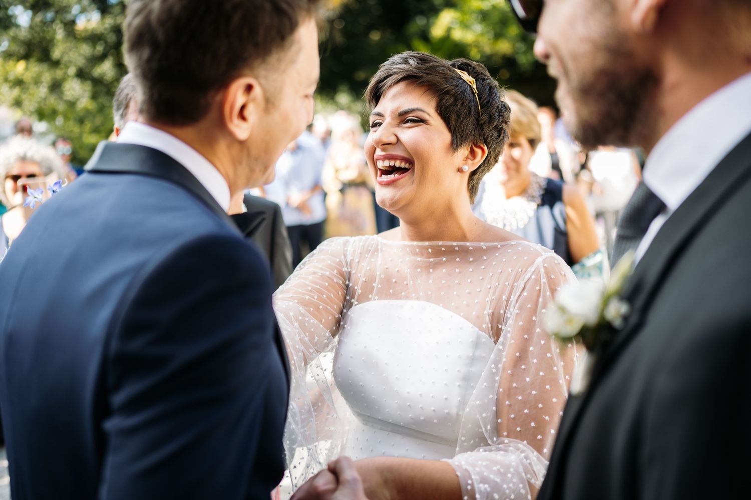 Wedding party members in formal attire share joyful moments during outdoor celebration.