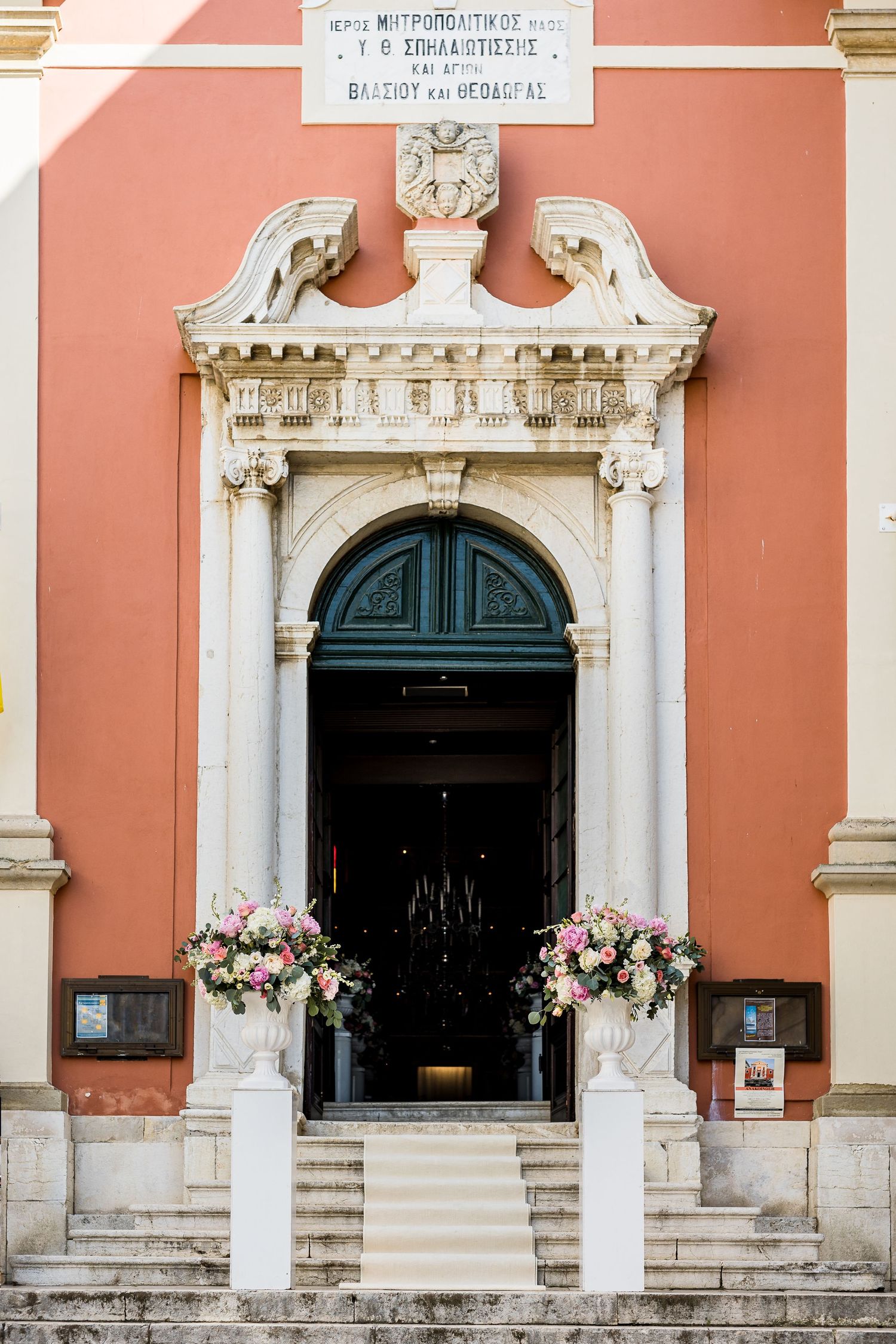 Pink building facade with ornate white stone doorways and architectural details.