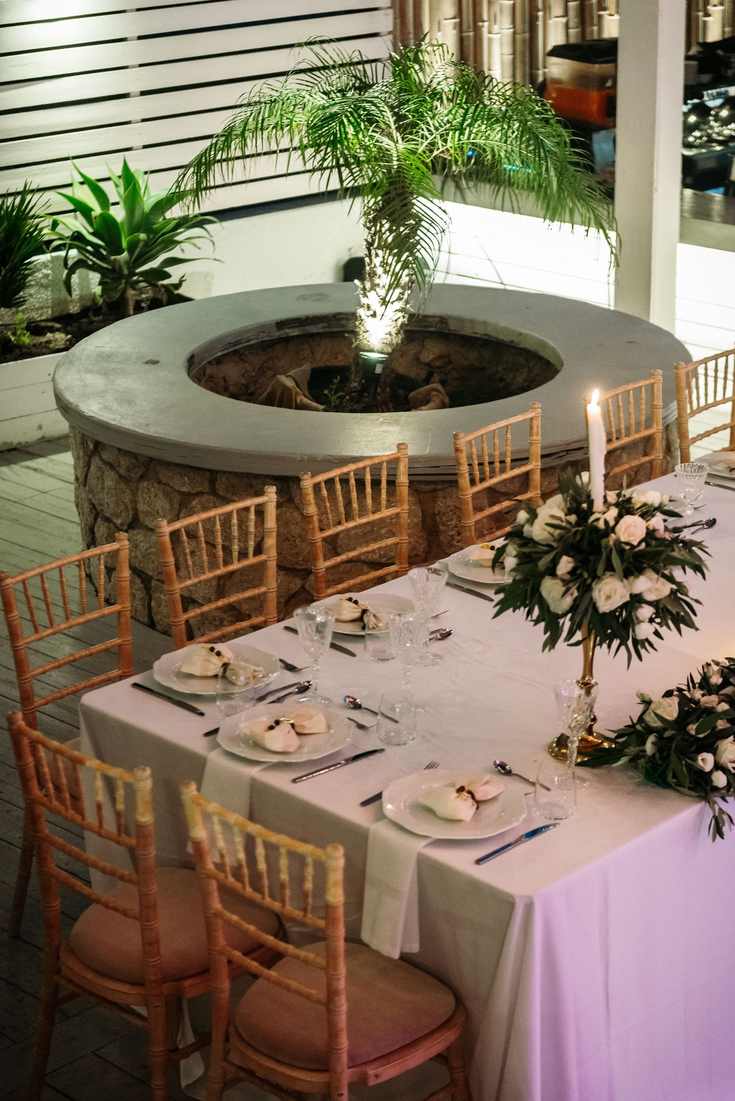 Elegant wedding reception setup with wooden chairs and white tablecloths.