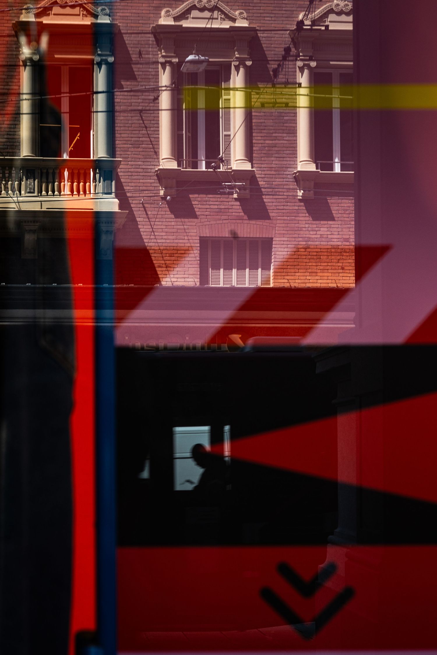 Abstract architectural reflection with red geometric shapes and classical building details.