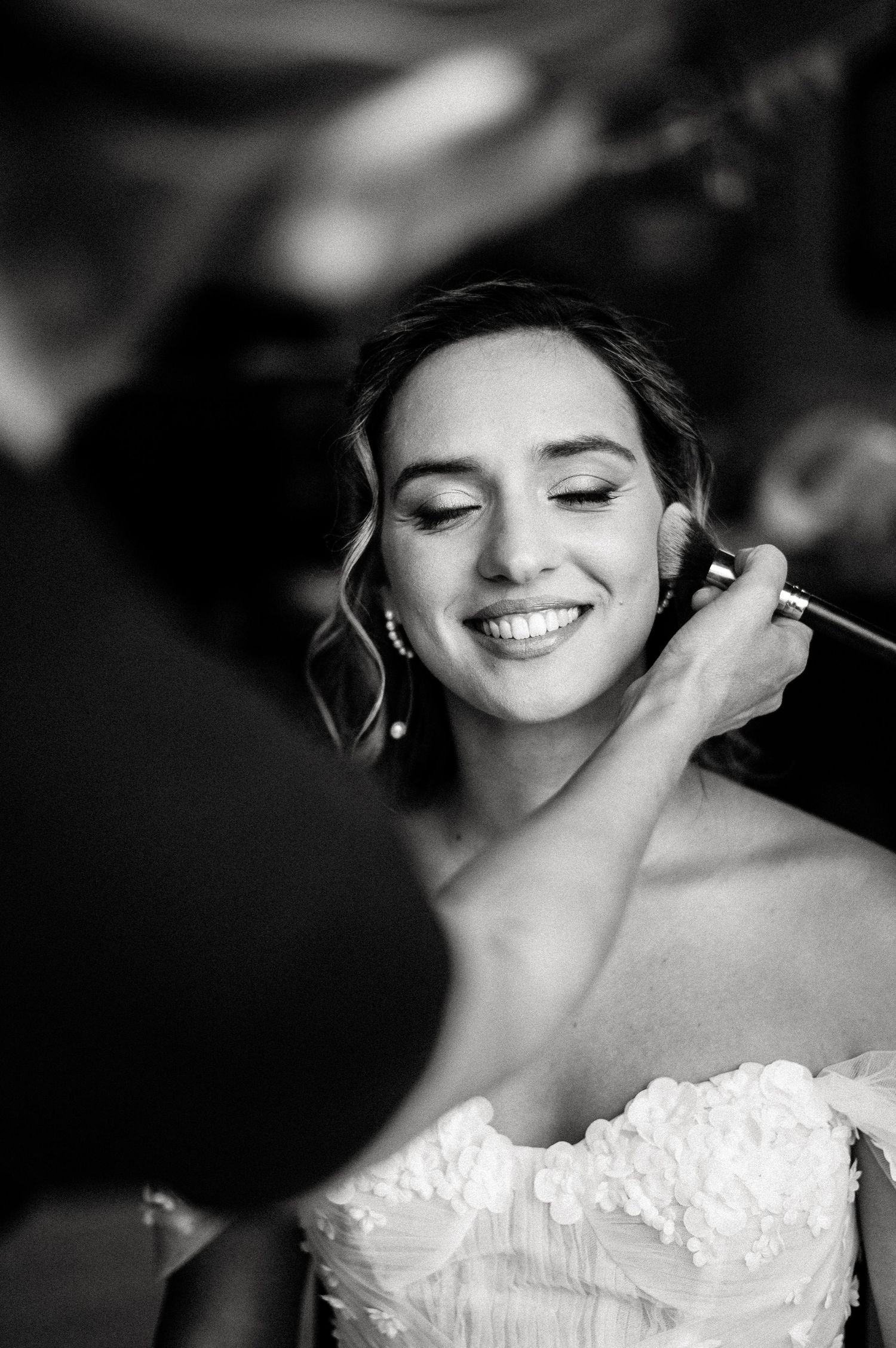 Black and white close-up shots capture the final touches of bridal makeup application.