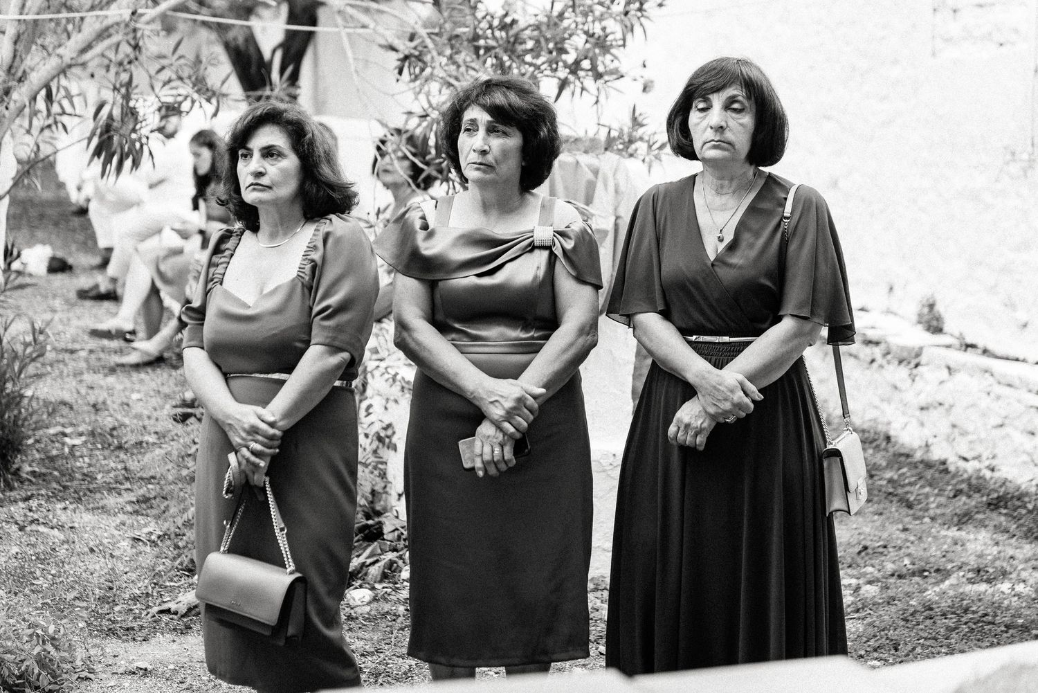 Black and white photo of wedding guests gathered outside during celebration.