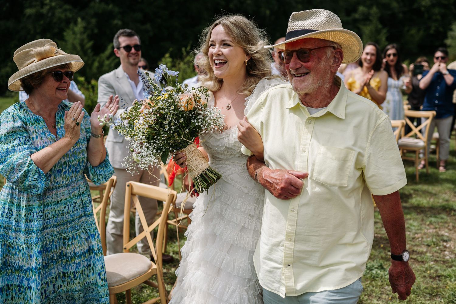 Joyful celebration during an outdoor wedding ceremony with guests clapping and cheering.
