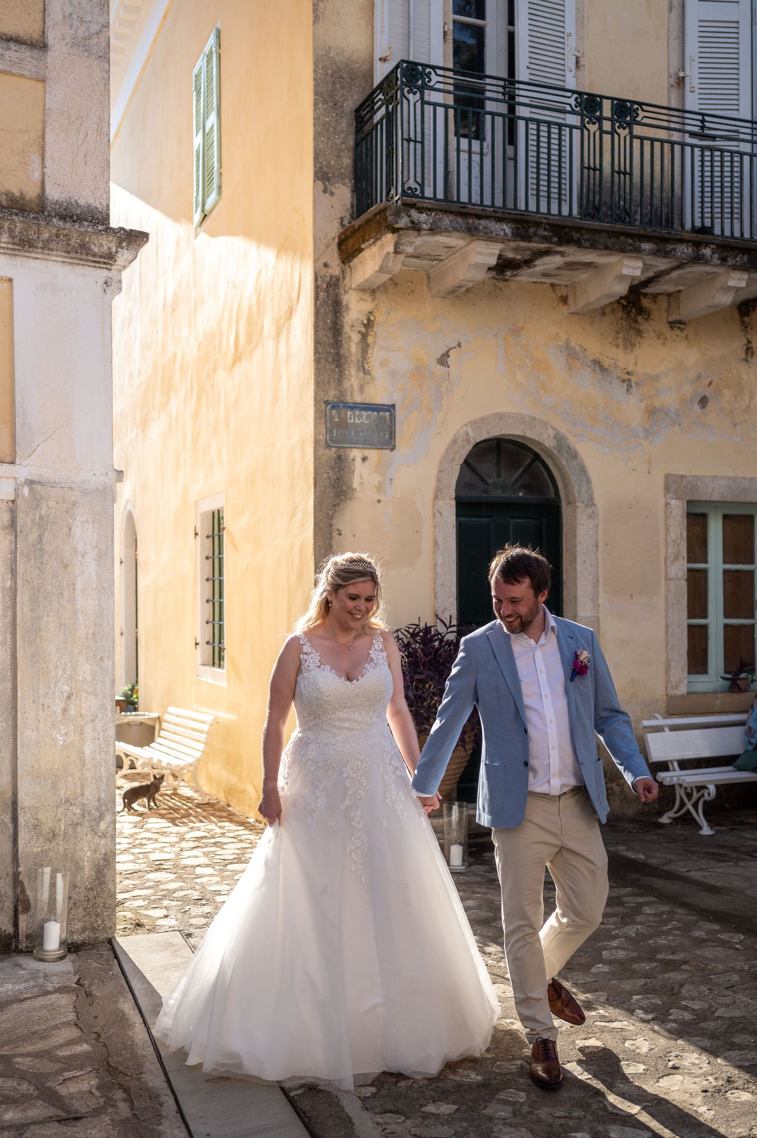 Couple strolling through a historic courtyard with peach-colored walls and classic architecture.