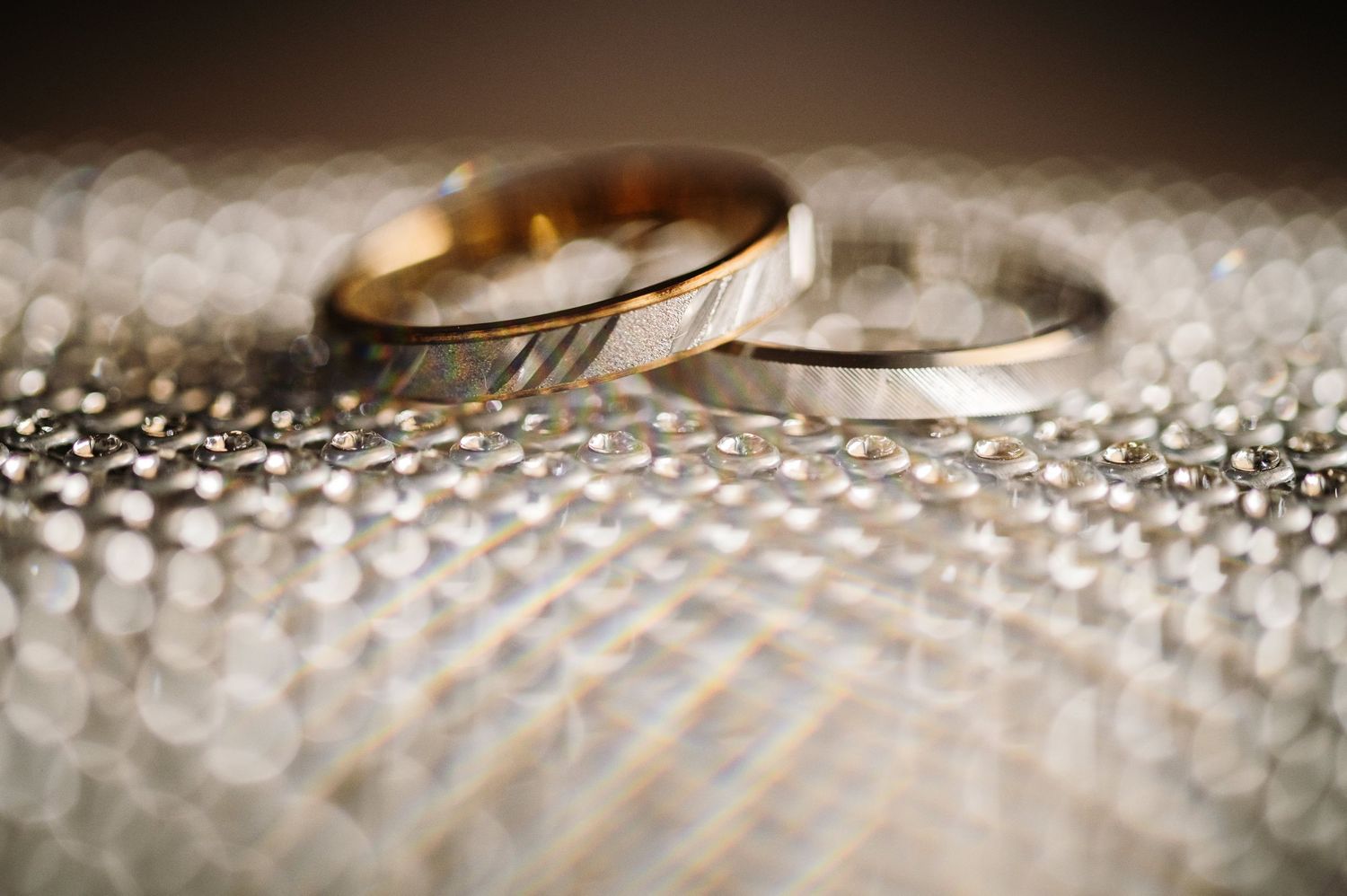 Macro shot of wedding rings on a textured sparkly surface with shallow depth of field.