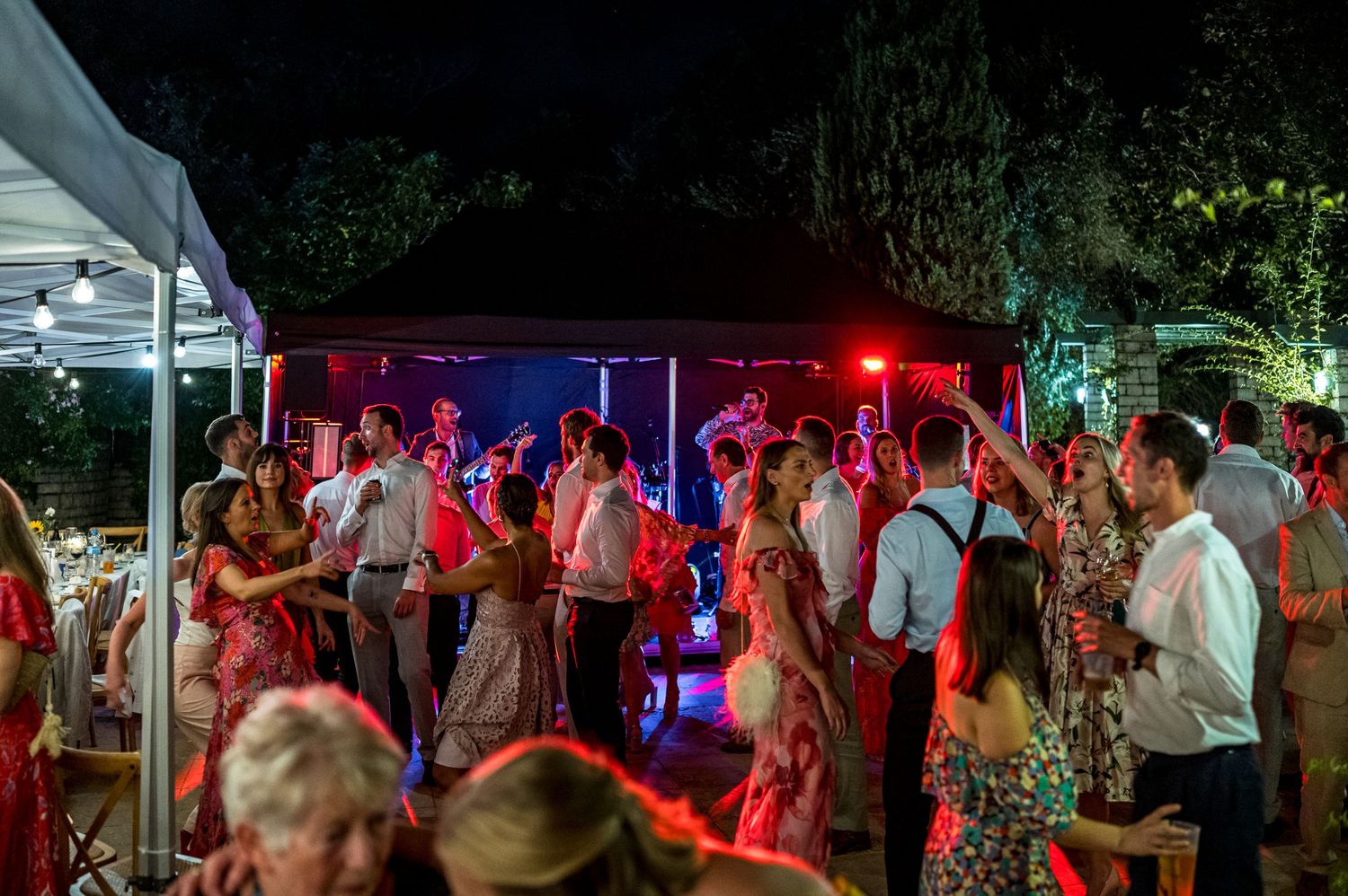 Outdoor evening party scene with red and blue lighting illuminating the dance floor.