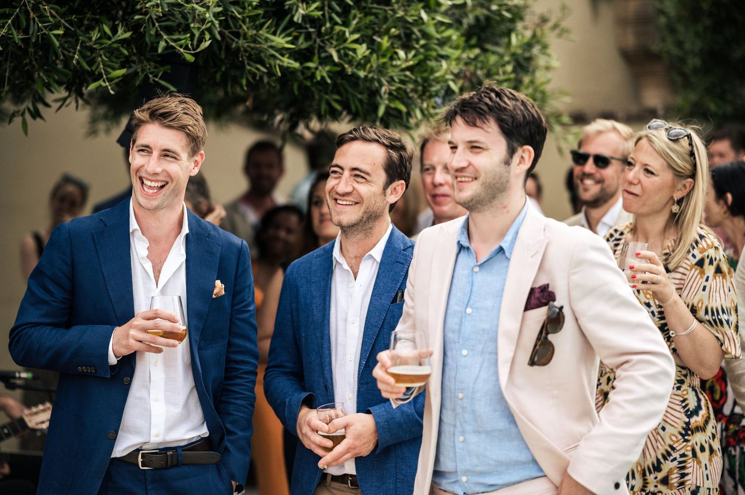 Stylishly dressed guests enjoying a wedding reception in summer attire.