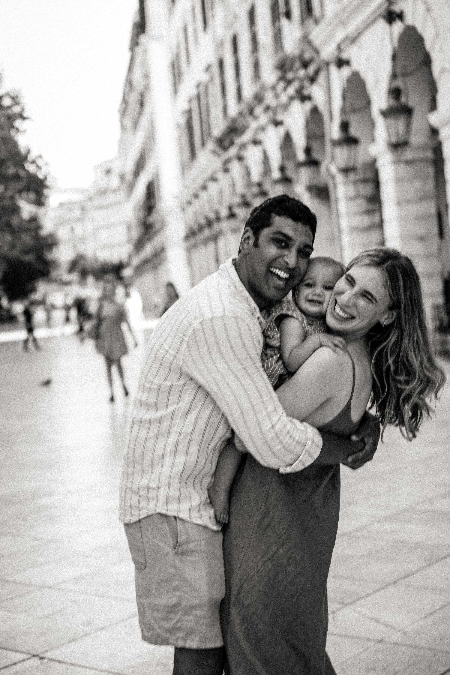 Joyful family embrace in black and white on historic European street.
