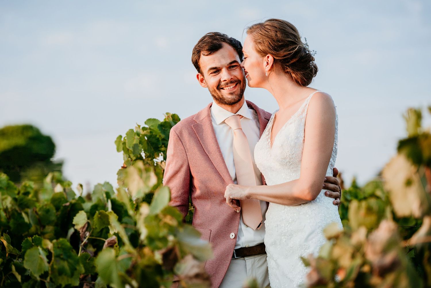 A couple shares an intimate moment among the grapevines on their wedding day.