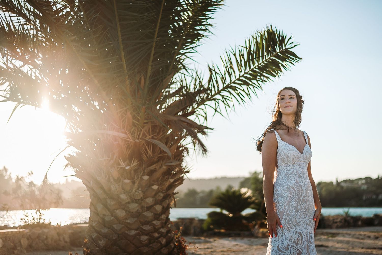 Palm fronds frame a romantic beach wedding scene at golden hour.