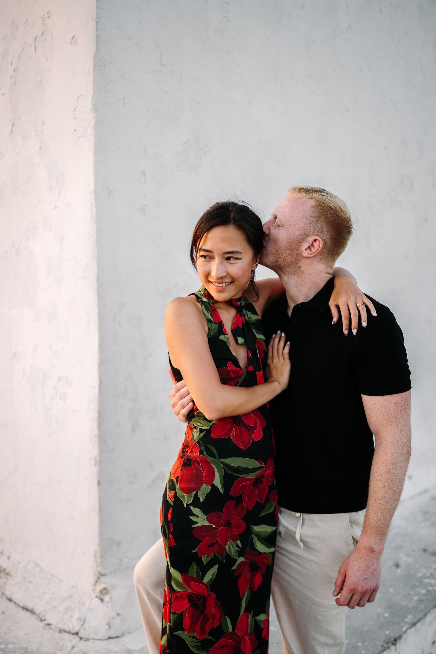 A couple sharing an intimate moment against a white wall backdrop.