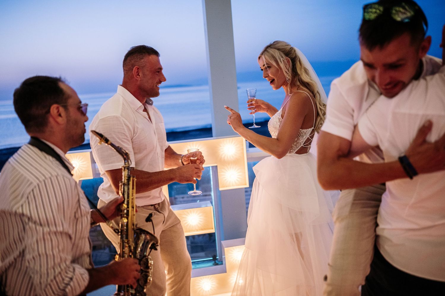 Wedding guests dancing and celebrating at beachfront reception.