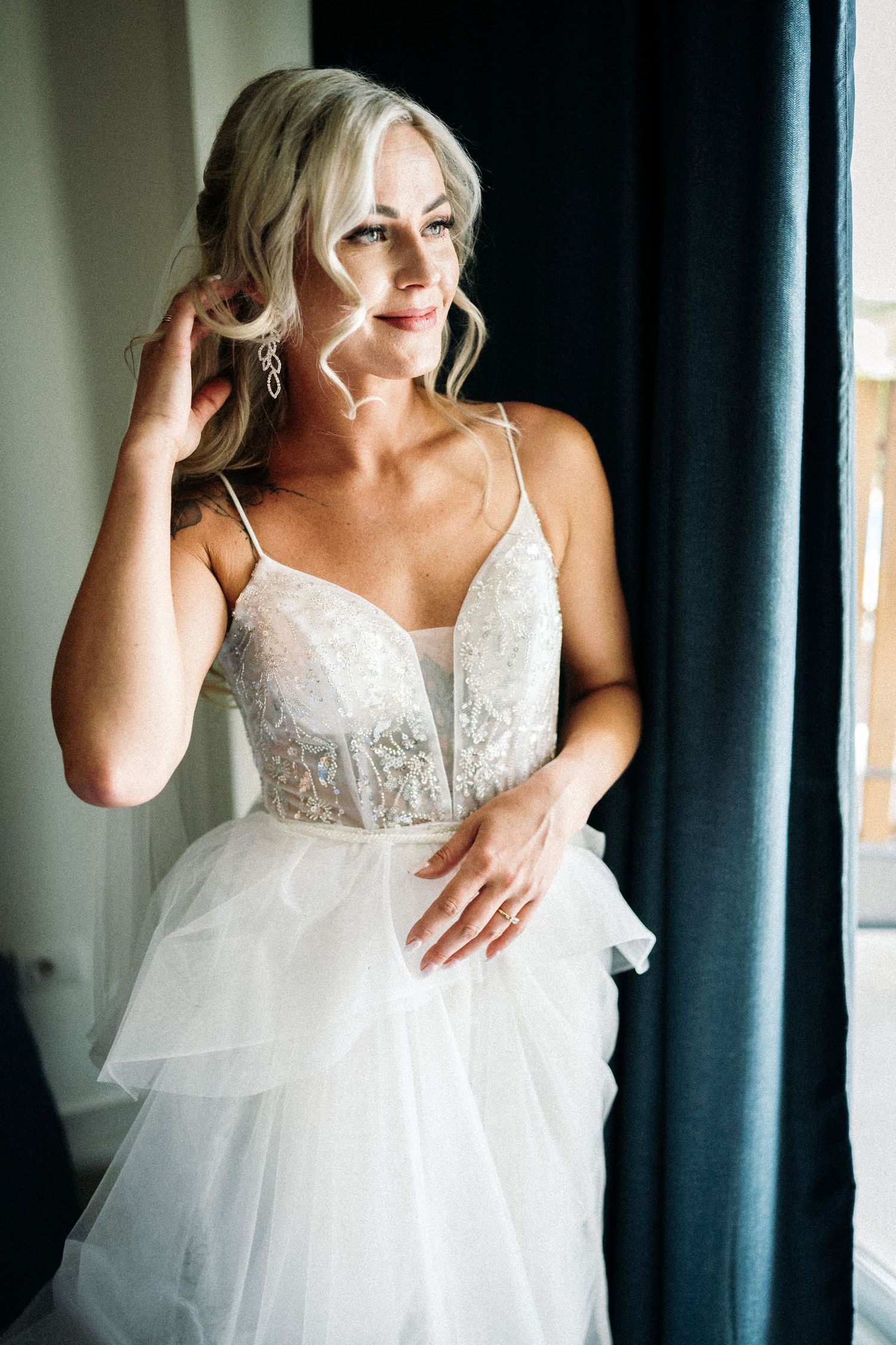 Candid moments of bridal preparation in a white lace gown against blue curtains.
