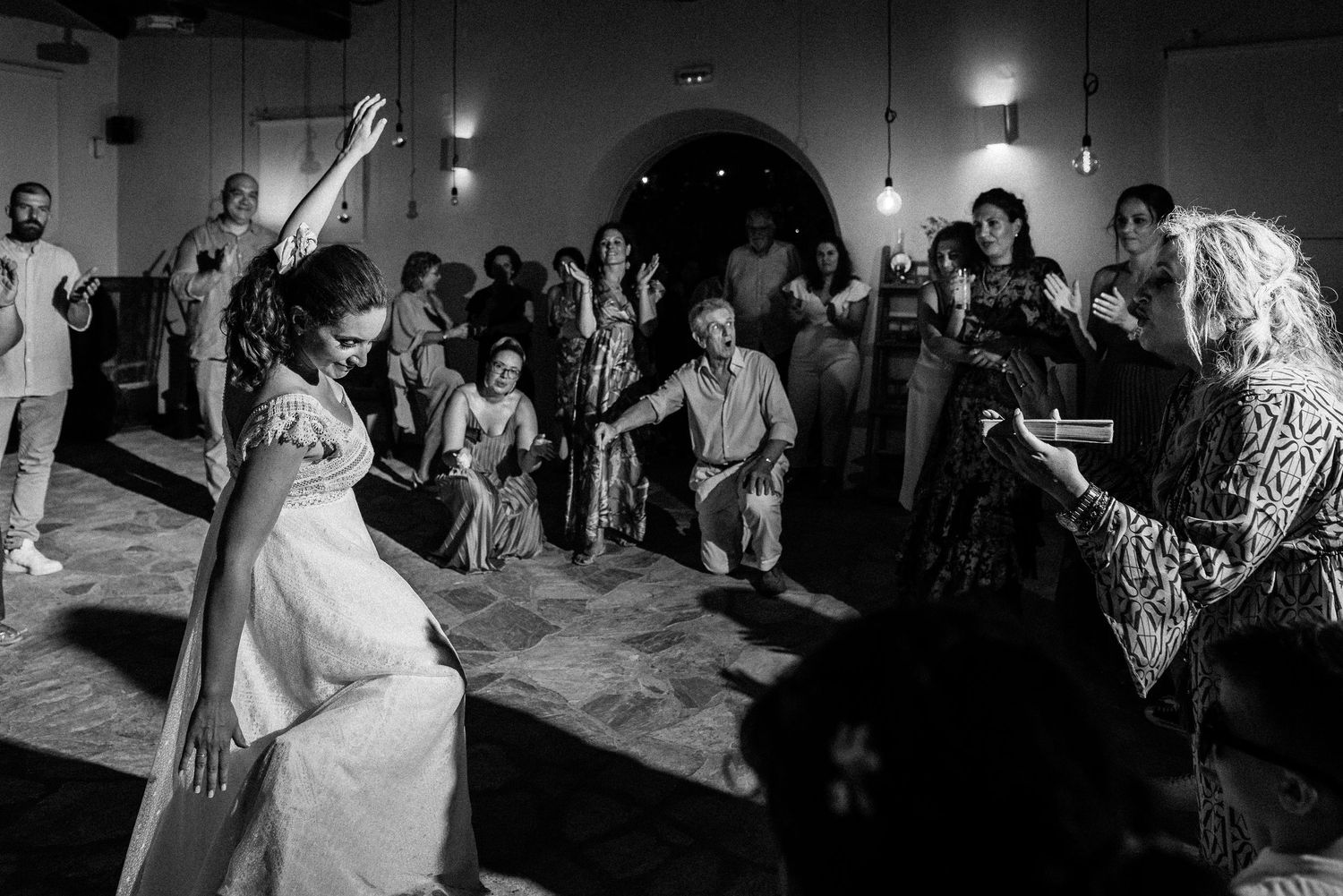 Black and white panoramic shot of a wedding reception dance floor filled with celebrating guests.