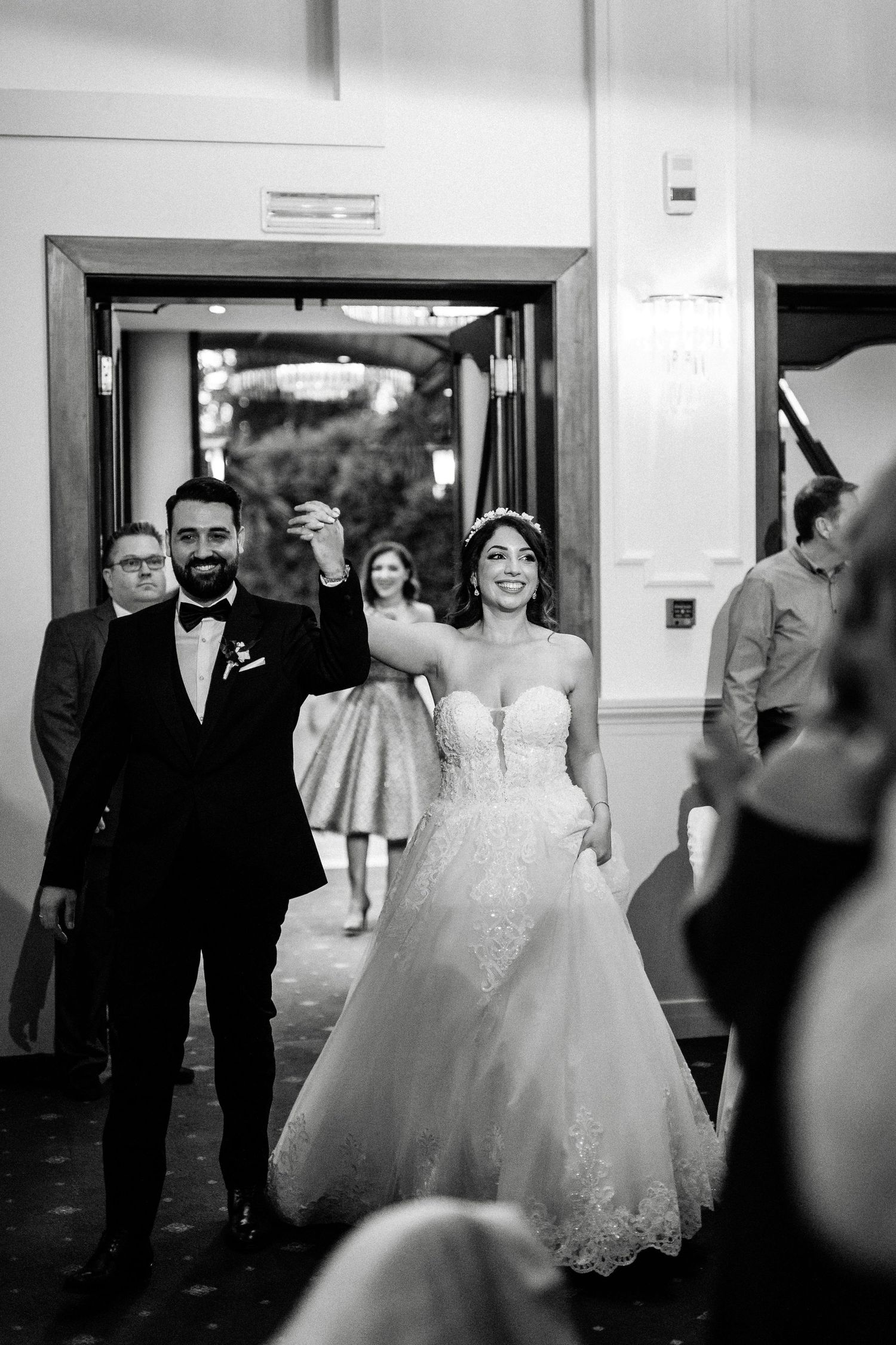 Wedding party walking down a hallway in formal attire with a bride in an elegant white ballgown.