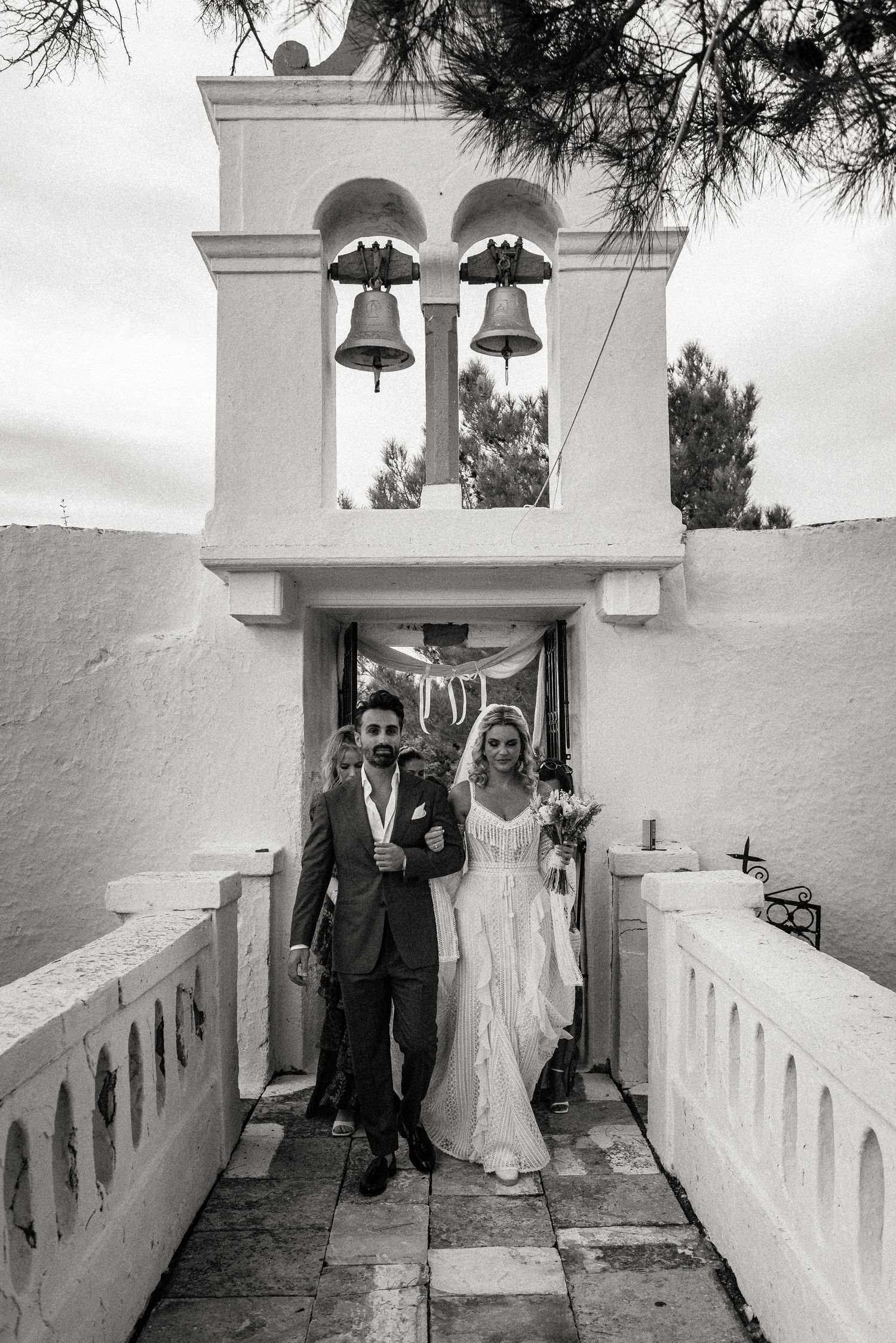 Traditional white Mediterranean church entrance with bell tower during wedding ceremony.