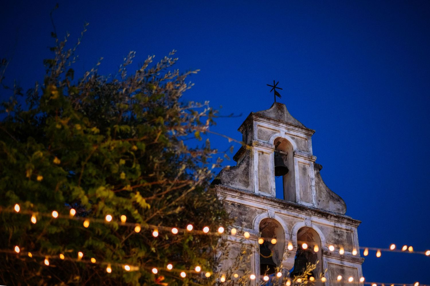 Church facade illuminated by string lights against deep blue twilight sky.