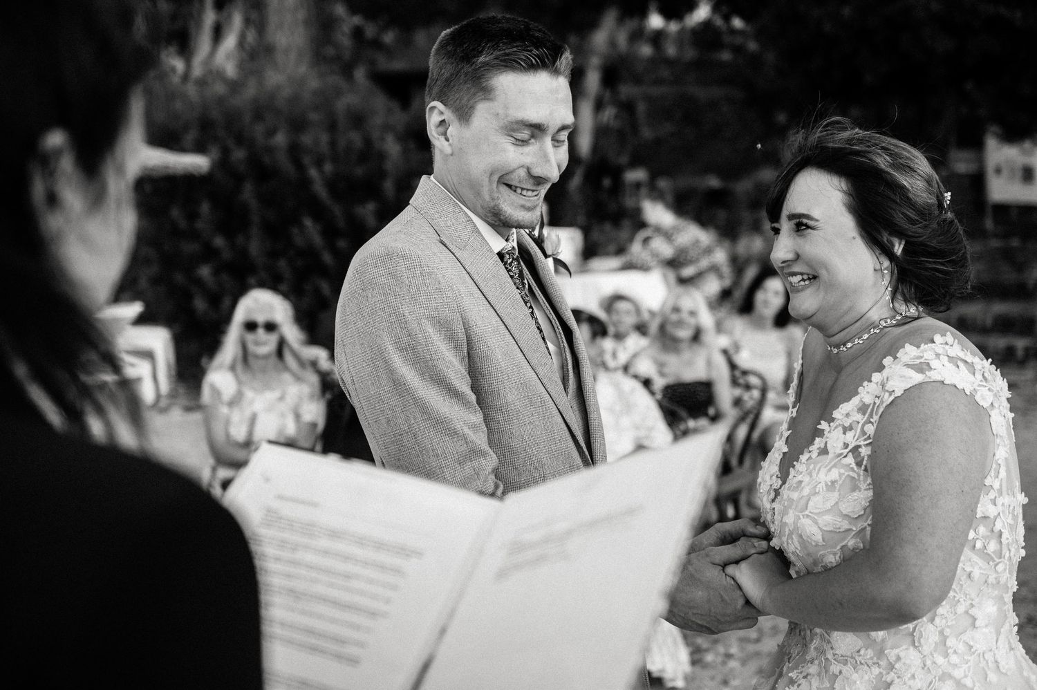 Wedding ceremony guests share joyful moments outdoors.