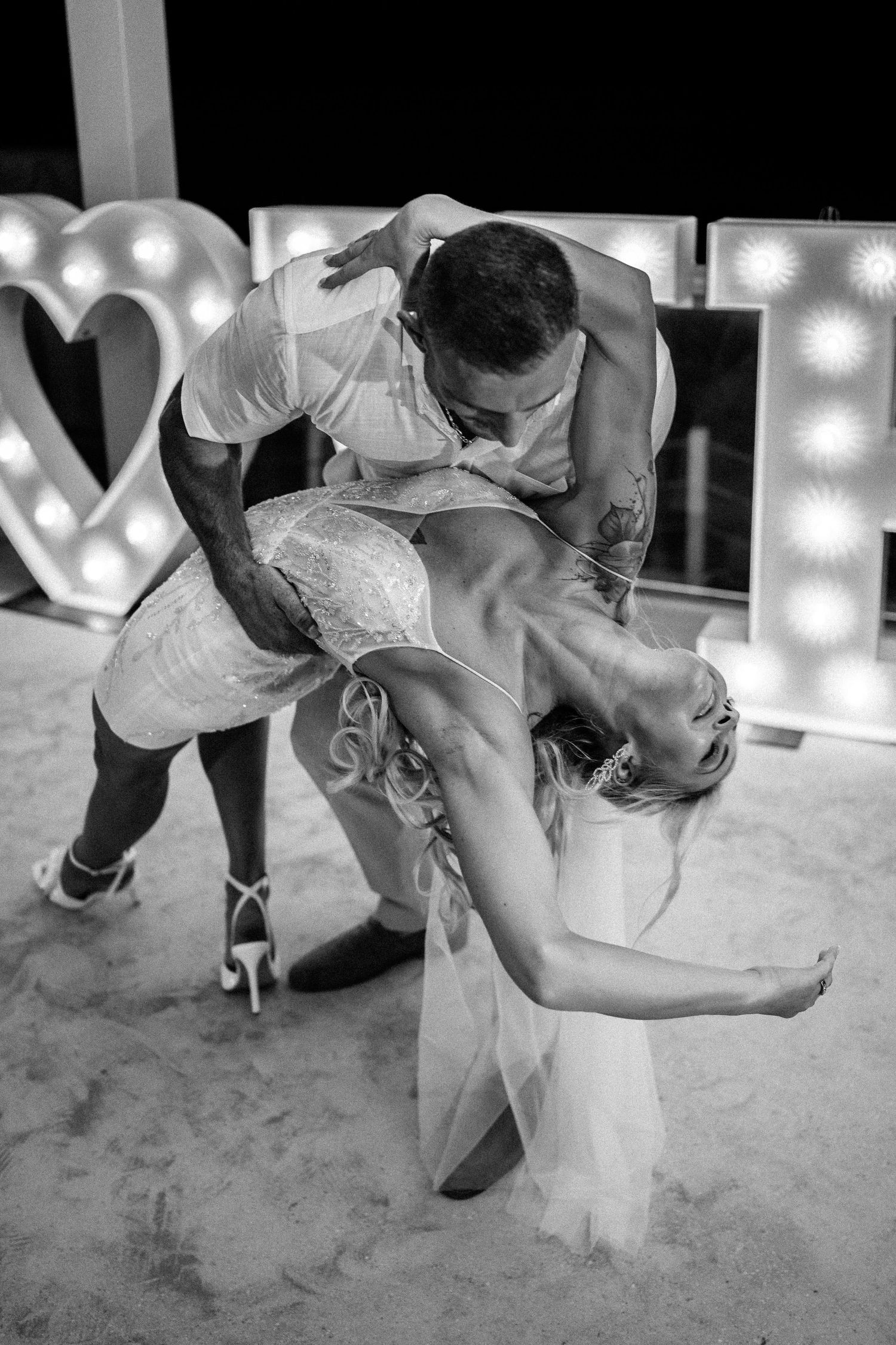 Black and white photo of romantic dance dip at wedding reception.