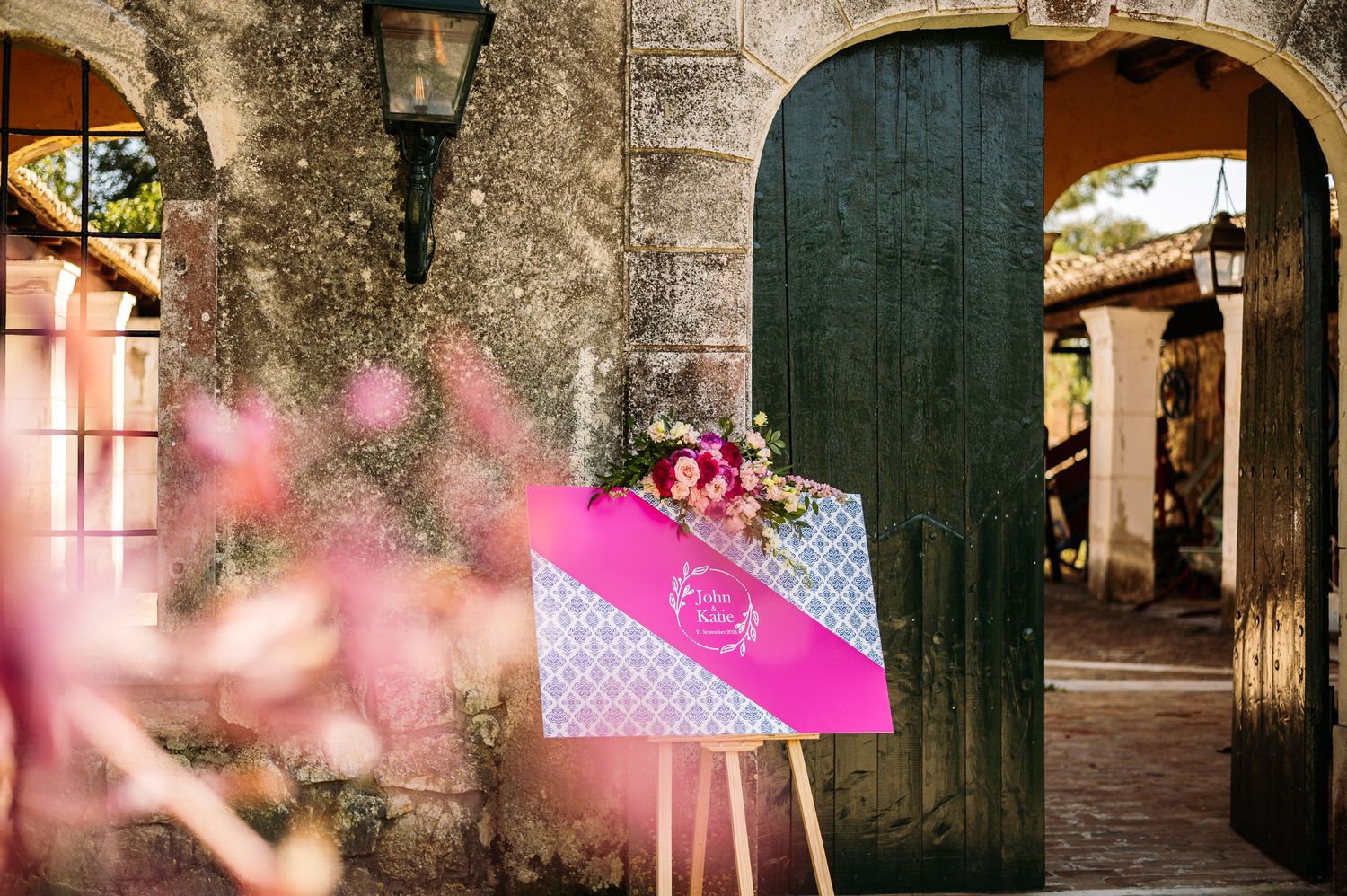 Stone archway with vintage lantern and pink decorative elements in historic venue.