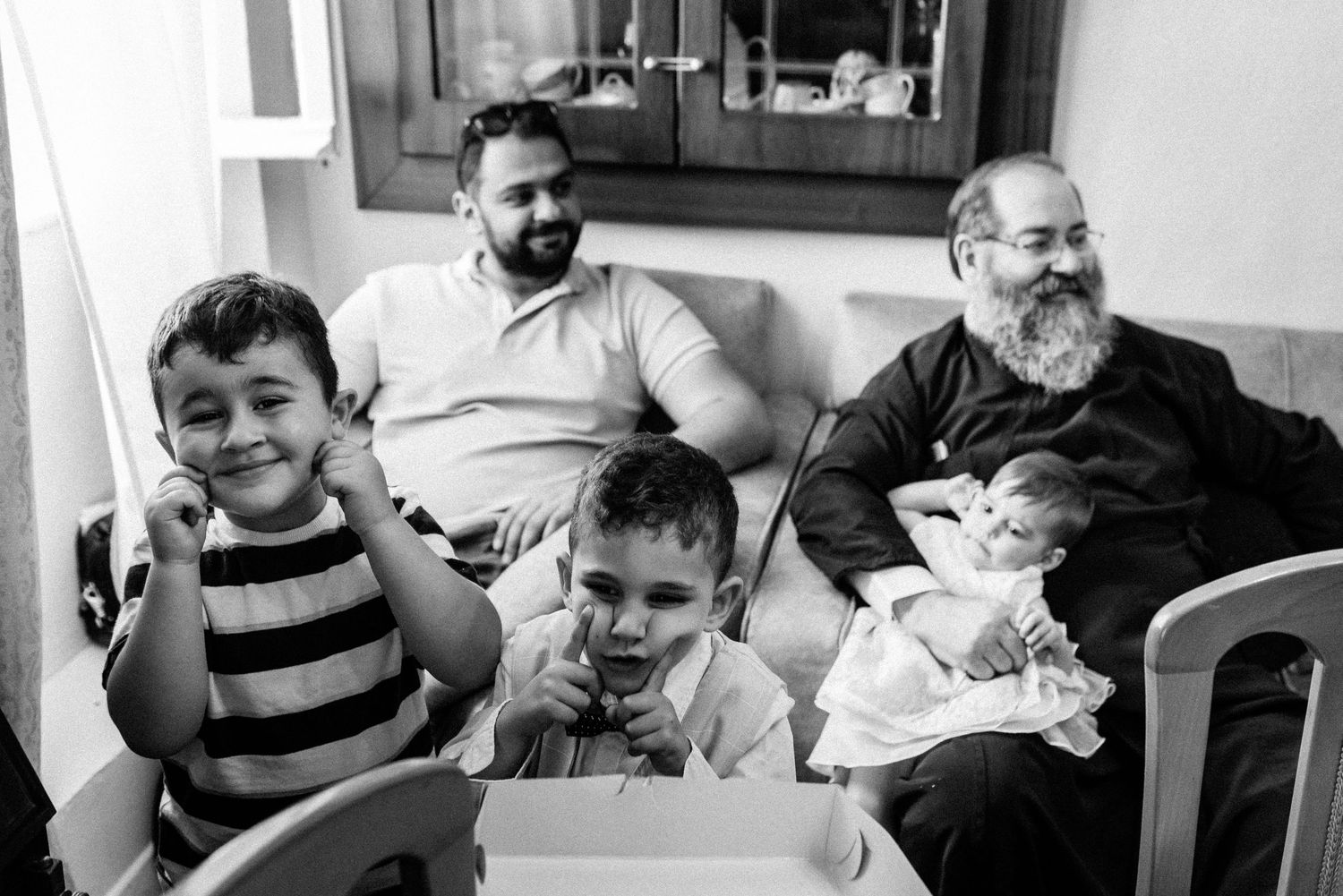 Three generations relax together on a couch while looking at something on a device.