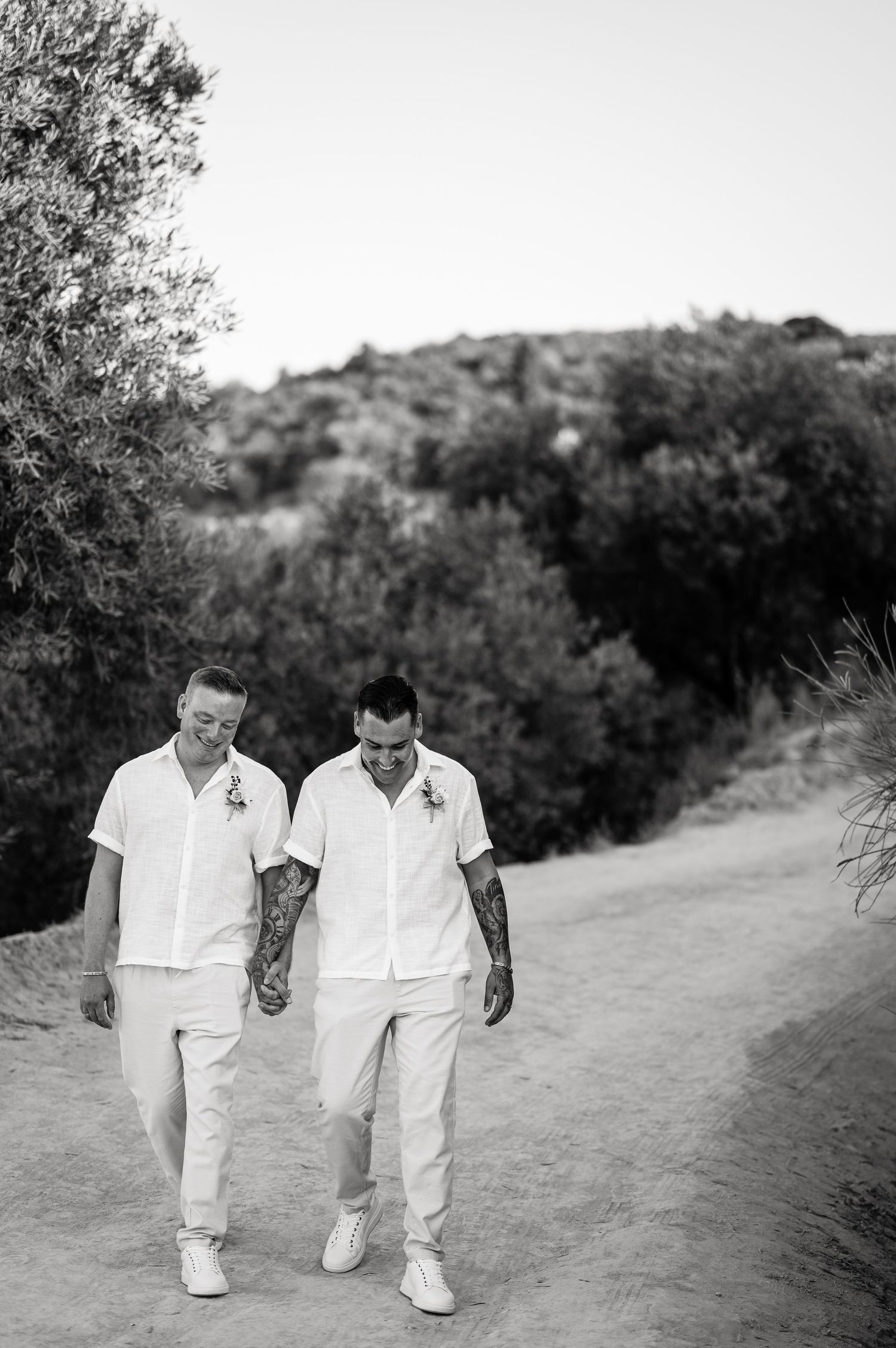 Black and white photo of couple walking together on winding hillside path.
