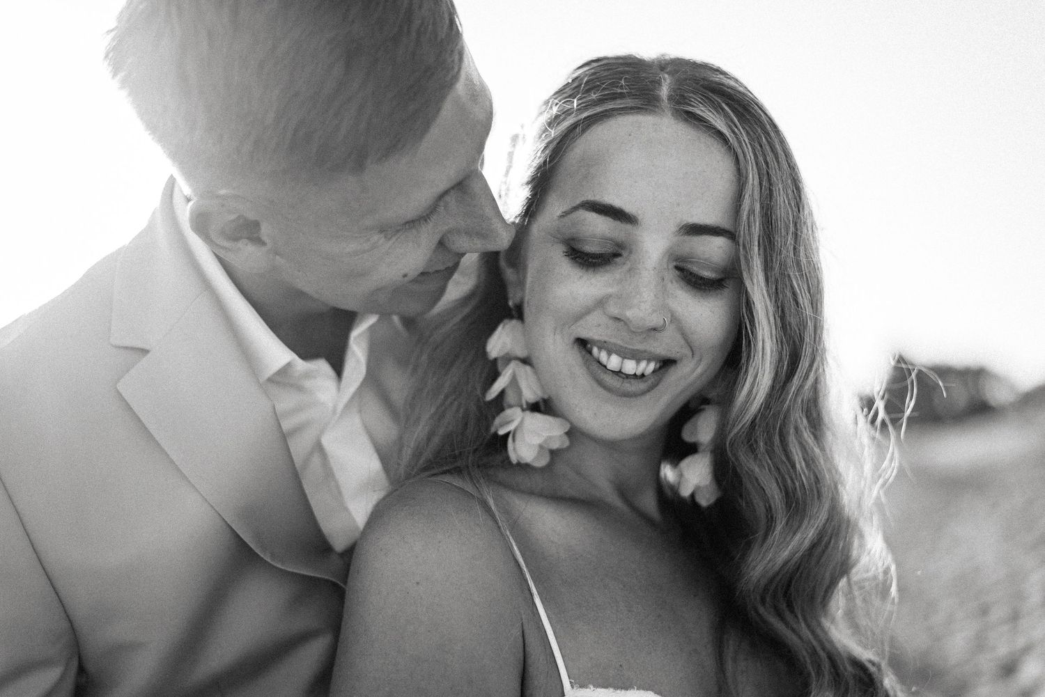 An intimate black and white portrait captures a romantic moment between newlyweds.