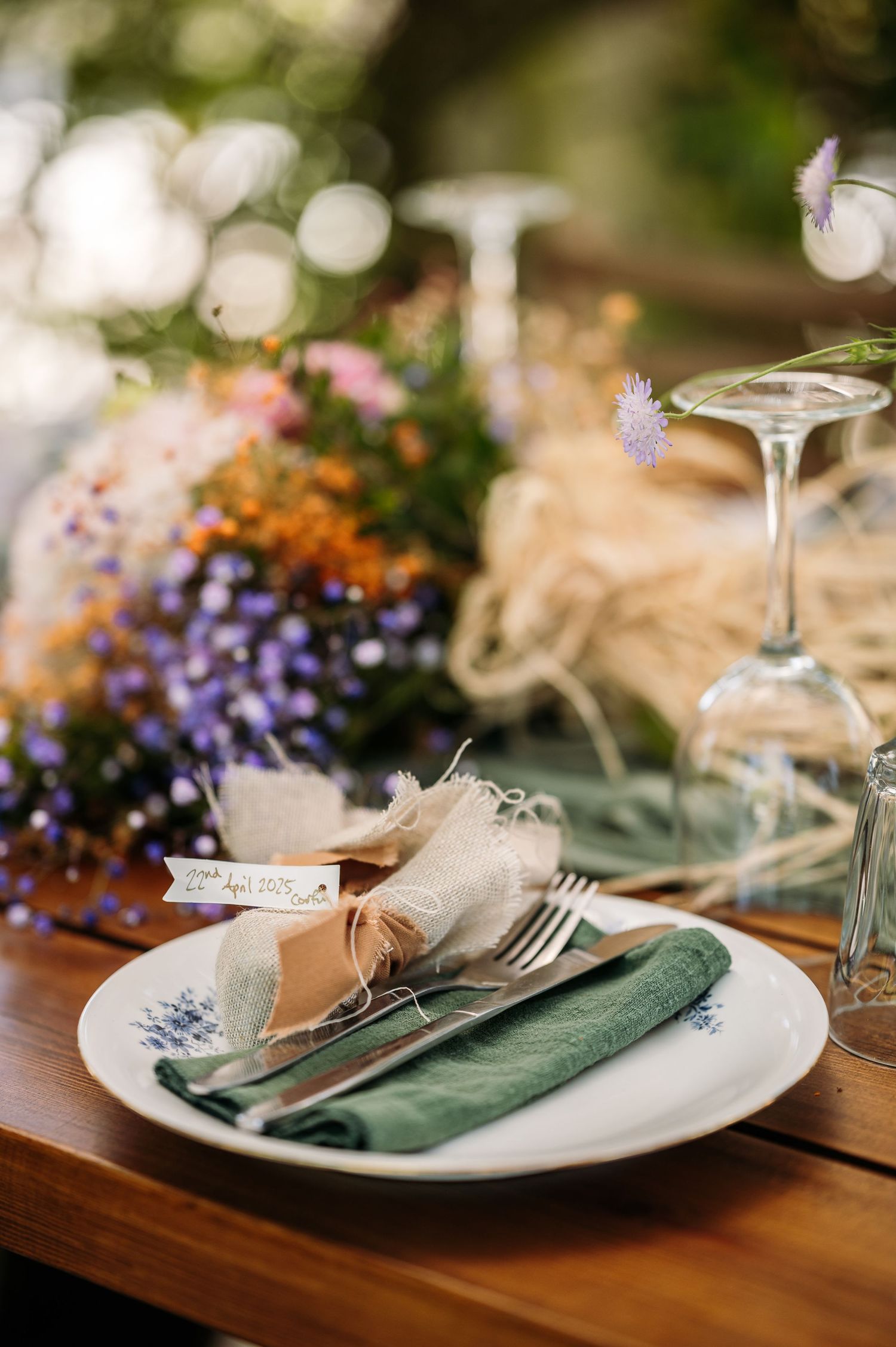 Place setting with green napkin and rustic decor against colorful wildflower arrangements.