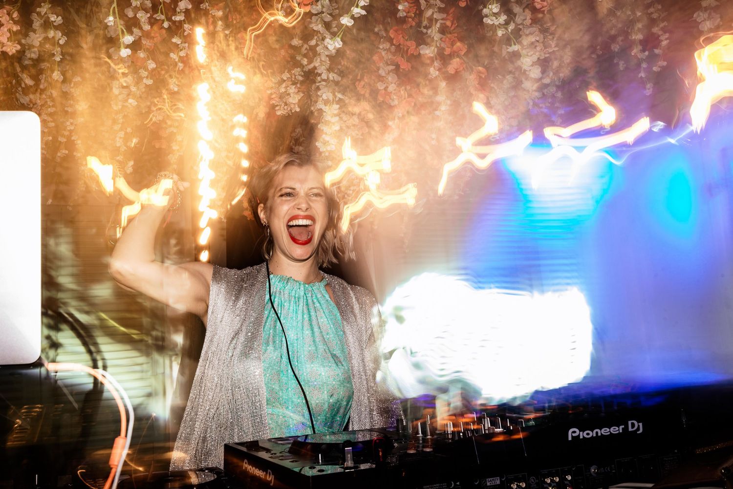 DJ equipment and dance floor illuminated with golden sparkler effects and blue lighting.