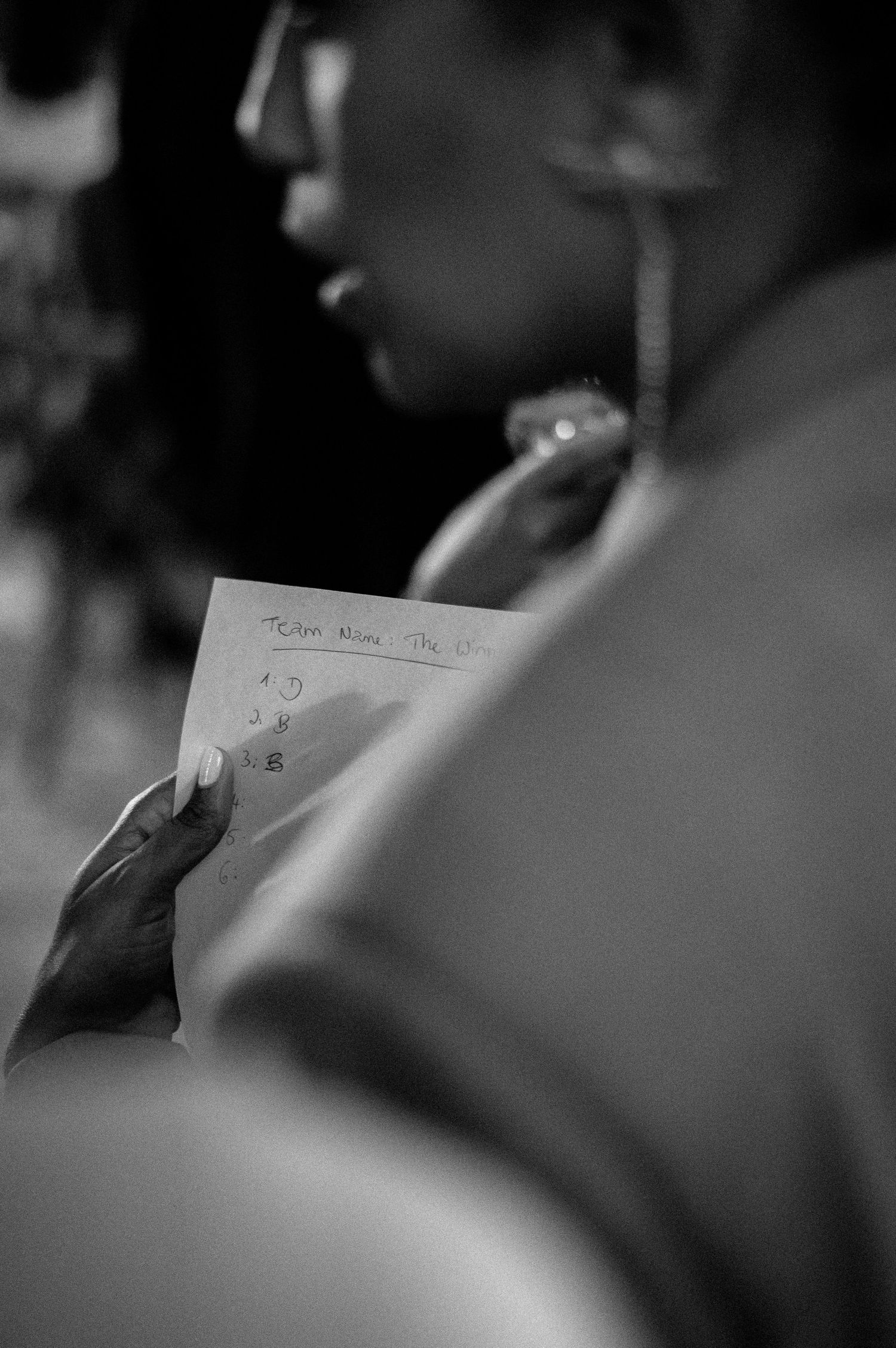 Black and white close-up of hands holding handwritten notes during a wedding ceremony.