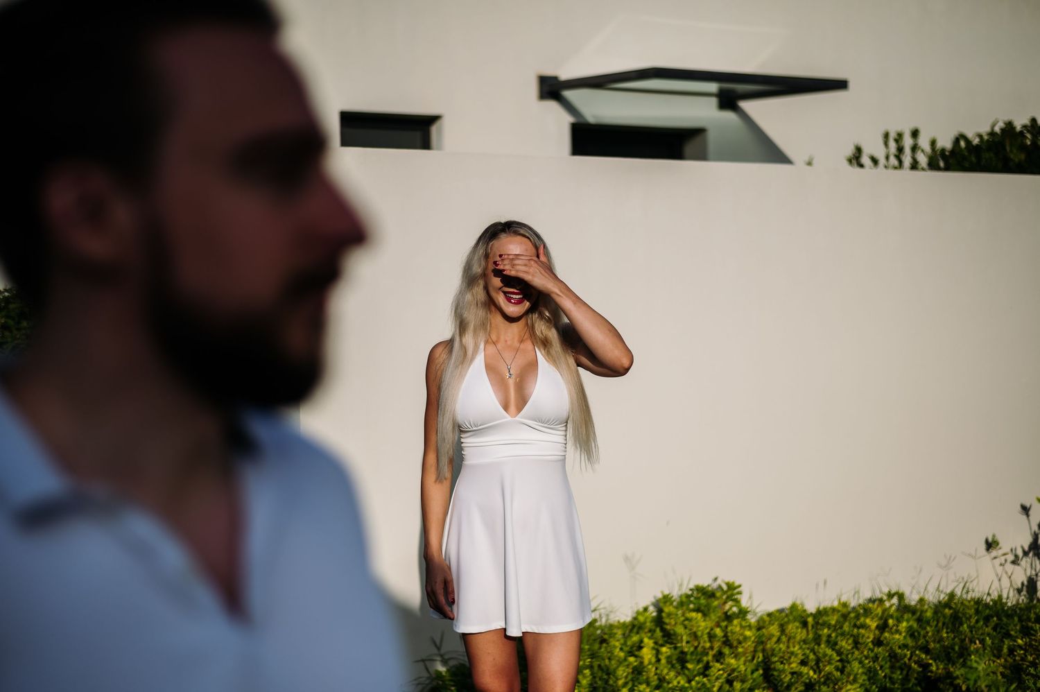 A romantic outdoor photoshoot featuring a couple in white against a light background.