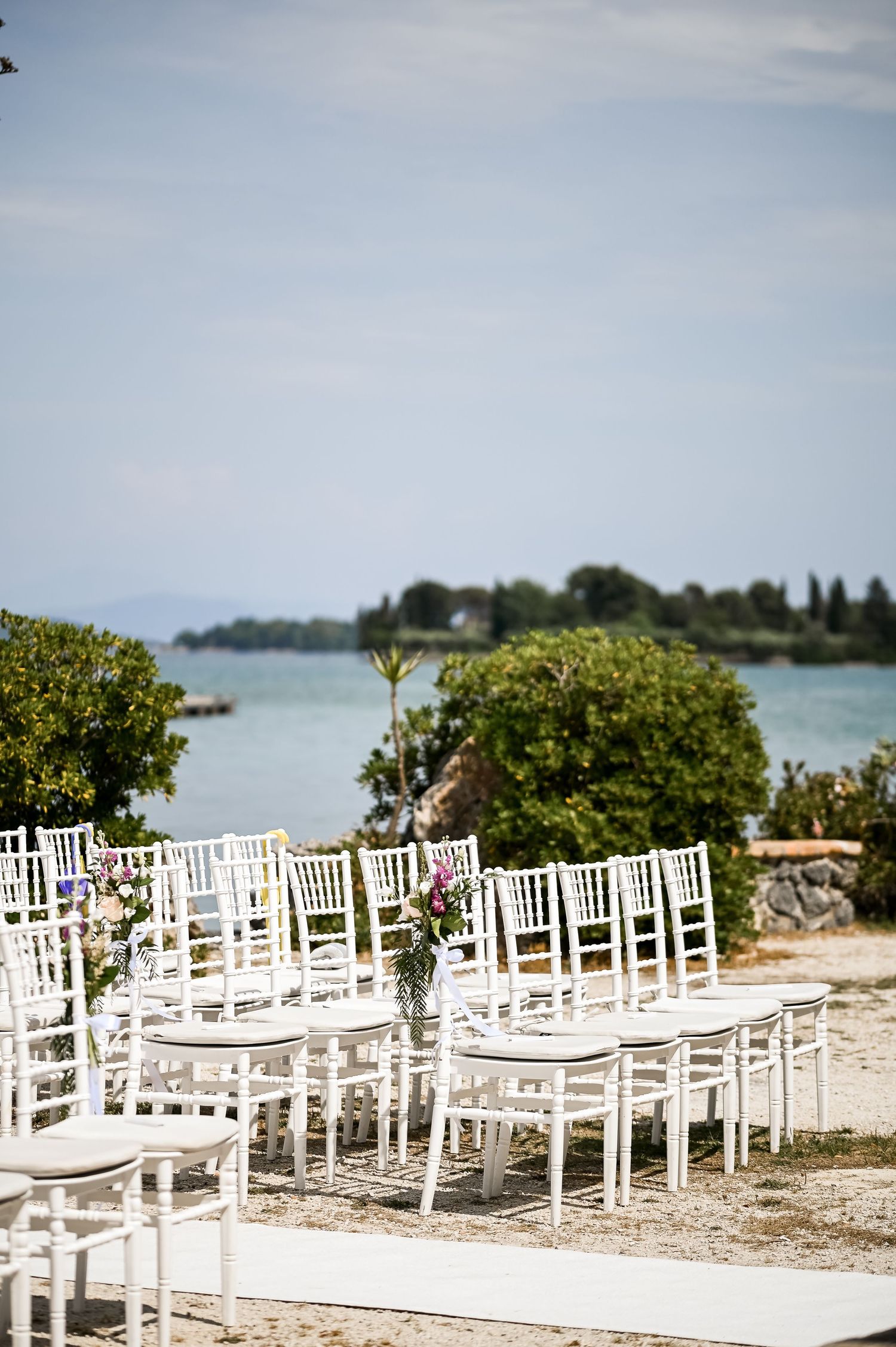 White chairs arranged in rows for a beachside wedding ceremony with ocean views.