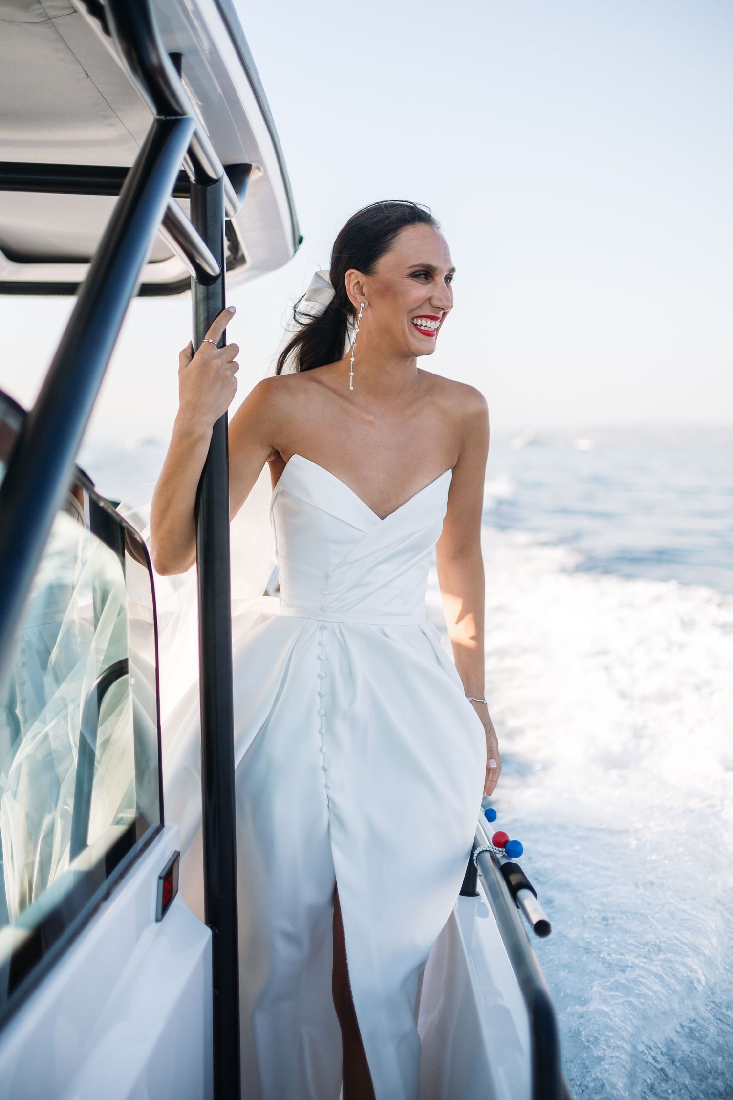 Elegant white wedding dress flows in the ocean breeze during a boat photoshoot.