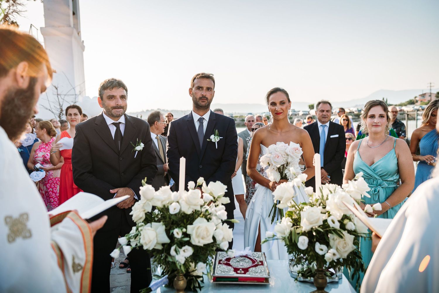 Wedding guests gathered outdoors for celebration with white floral arrangements and decorations.